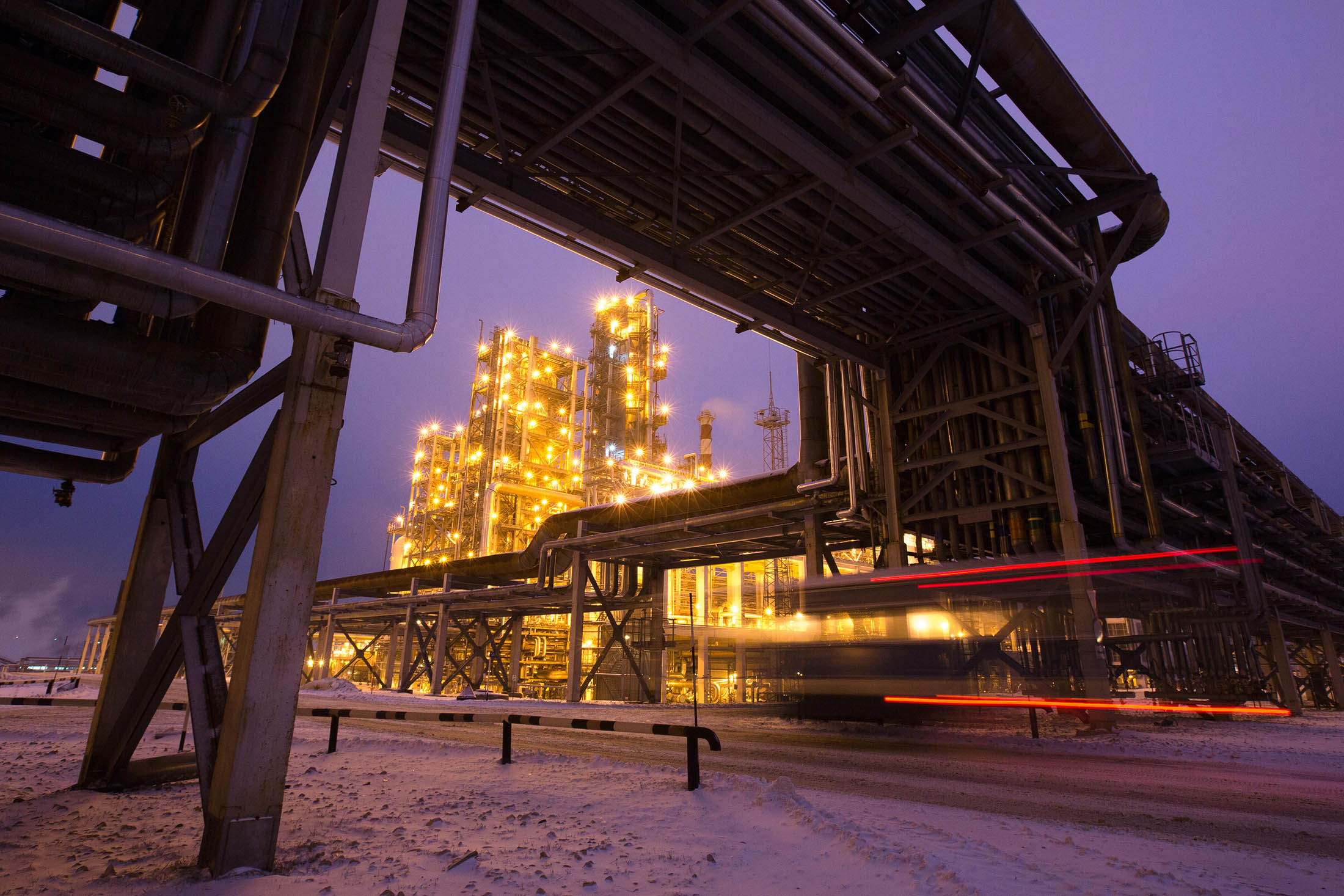 A light trail from an automobile passes beneath overhead pipework near illuminated petroleum cracking towers at the Lukoil-Nizhegorodnefteorgsintez oil refinery, operated by OAO Lukoil, in Nizhny Novgorod, Russia, on Thursday, Dec. 4, 2014. Crude slumped 18 percent last month as the Organization of Petroleum Exporting Countries maintained its output quota, letting prices decrease to a level that may slow U.S. production.
