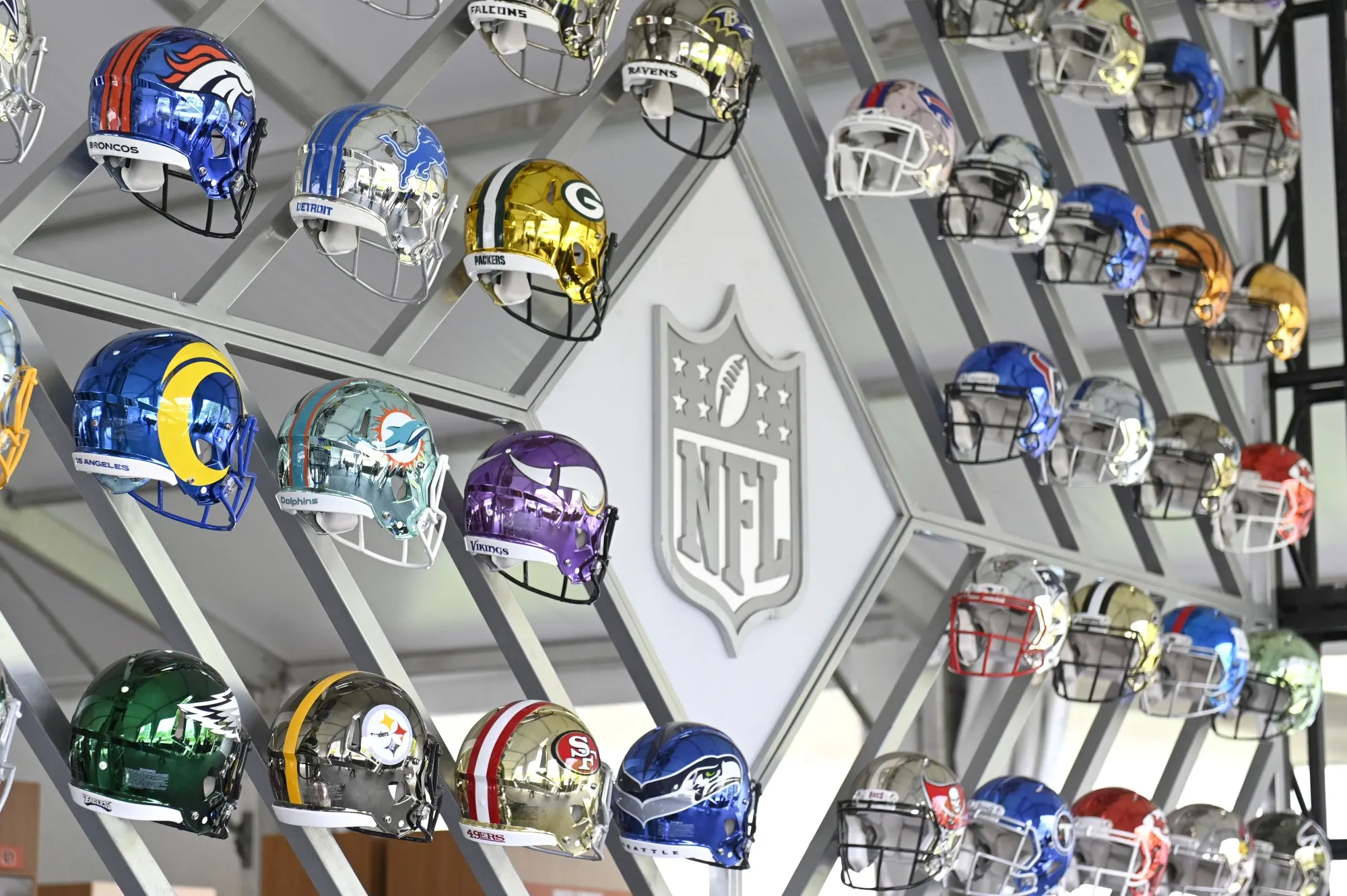 A wall of NFL team helmets on display.