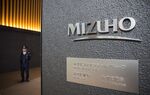 A security stands at the entrance to the Mizuho Financial Group Inc. headquarters in Tokyo, Japan, on Friday, April 21, 2017. Mizuho is scheduled to release full-year earnings figures on May 15.