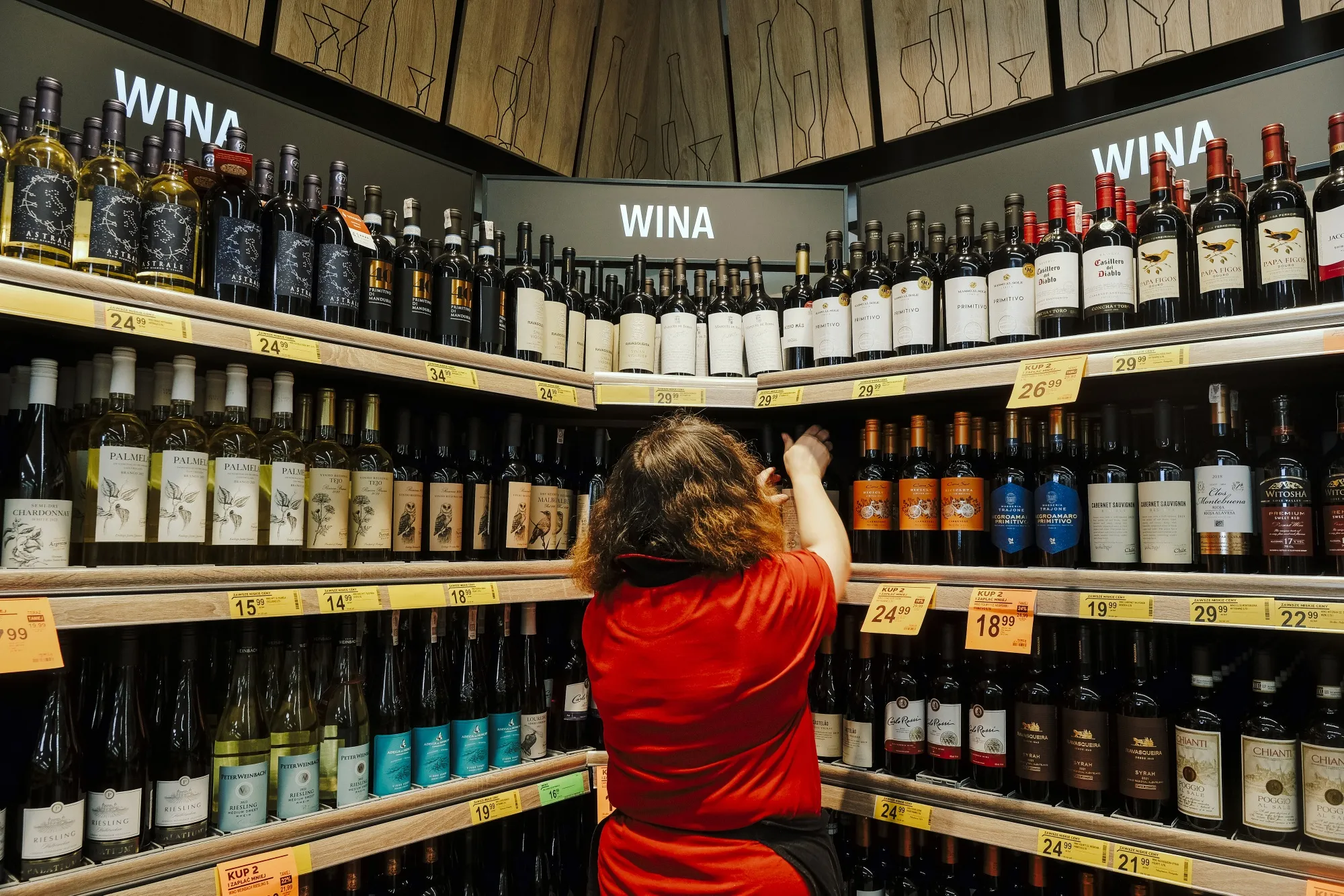 An employee&nbsp;stocks shelves in the wine section inside a supermarket in Warsaw.