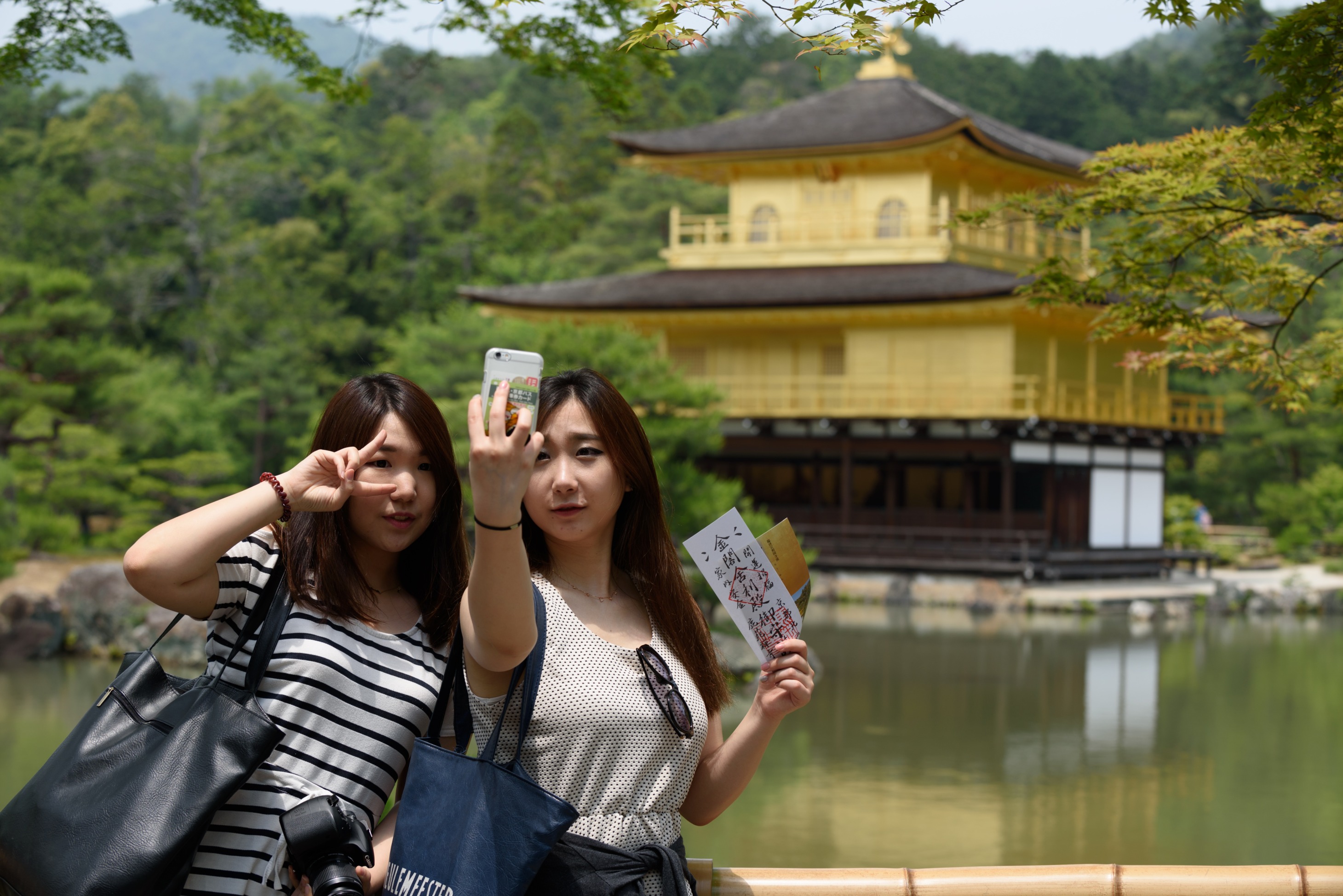 Tourists pose for a selfie in front of the Kinkakuji temple in Kyoto.