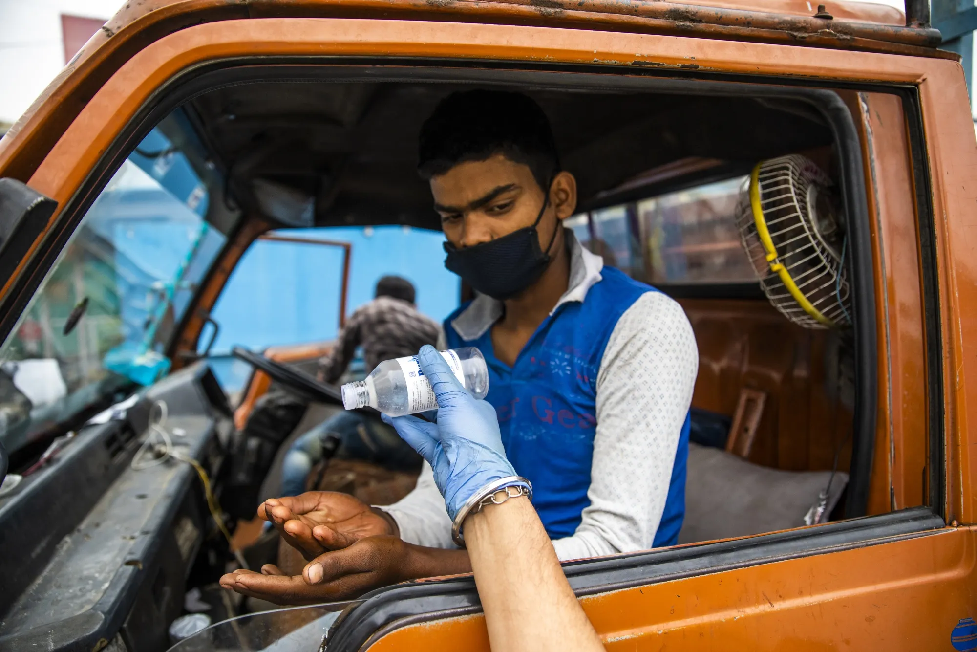 Security guards pours disinfectant into the hands of a worker arriving by truck as he enters Ajit Industries factory in Haryana, April 20.