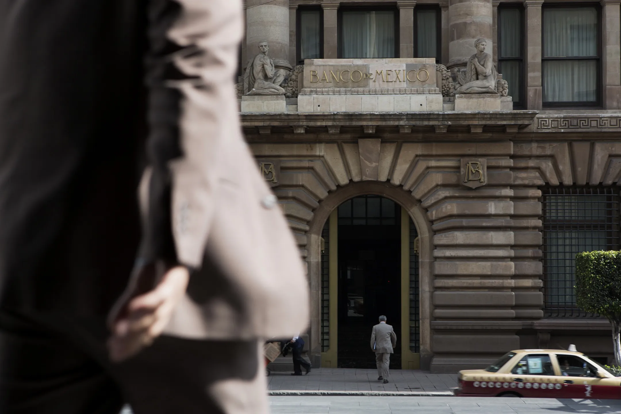 Pedestrians walk in front of Banco de Mexico headquarters in Mexico City.
