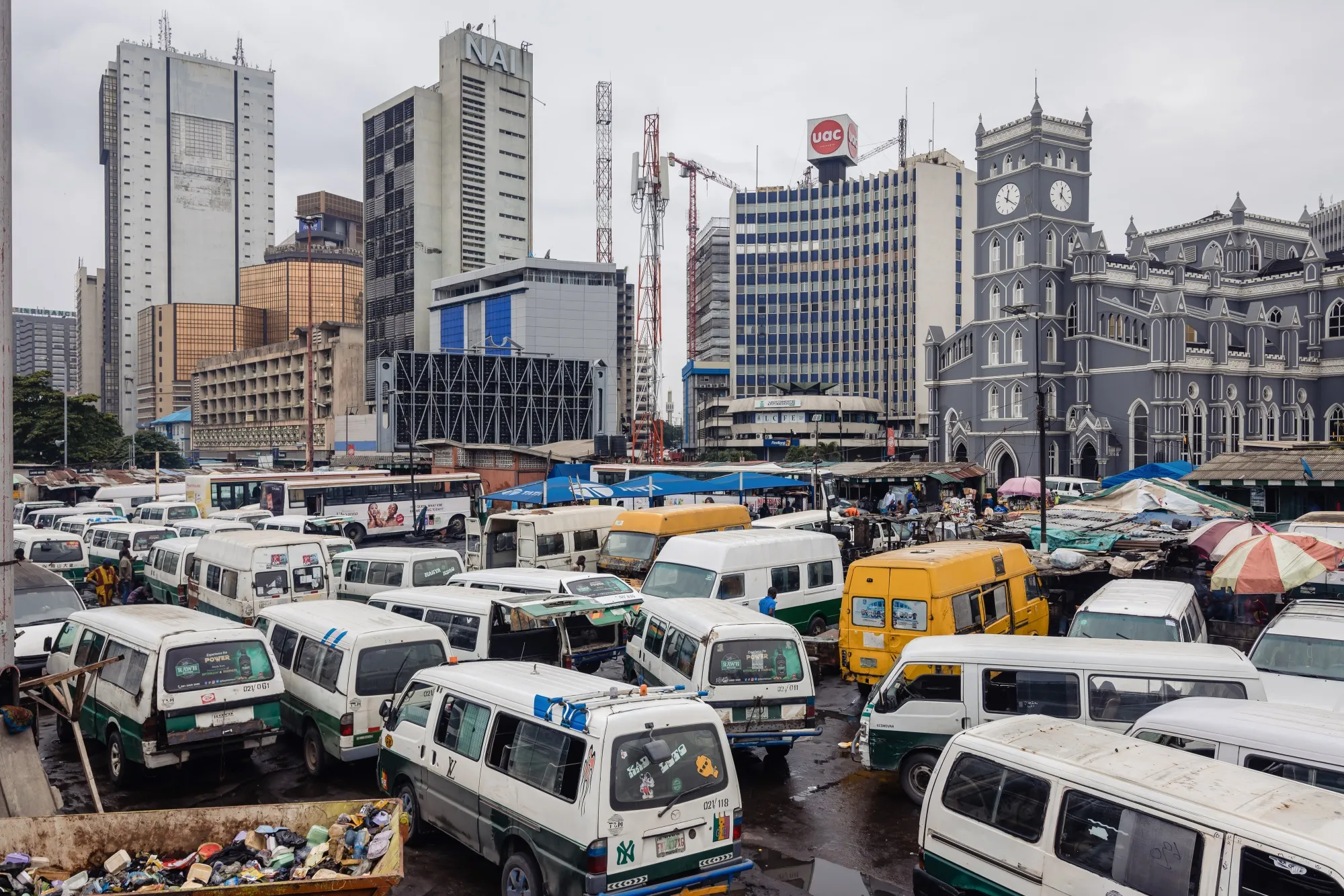 Taxi vans parked near commercial office buildings in the Central Business District of Lagos.