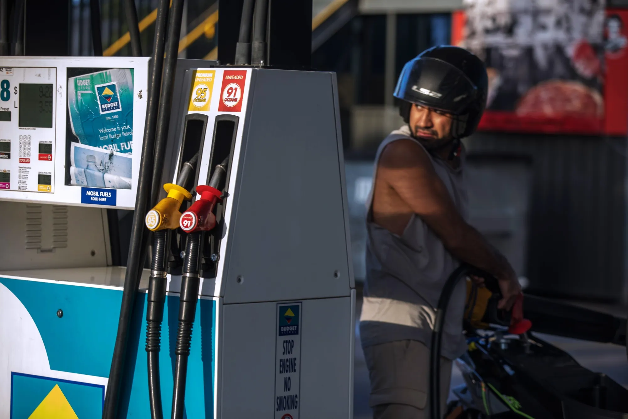 A customer refuels a motorcycle at a petrol station in Sydney.