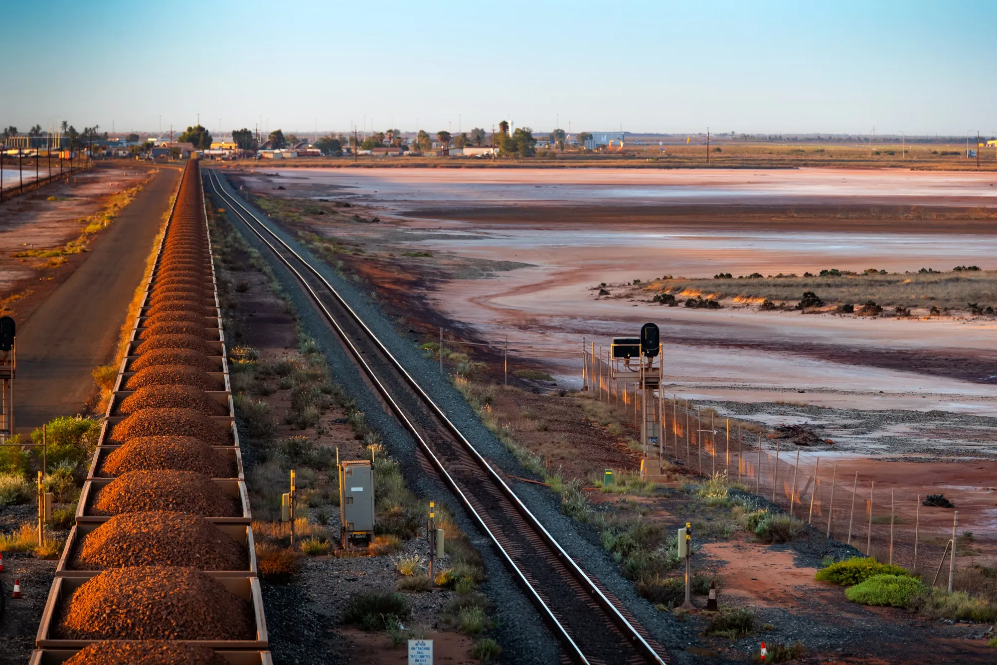 A freight train carrying iron ore travels along a rail track towards Port Hedland, Australia.