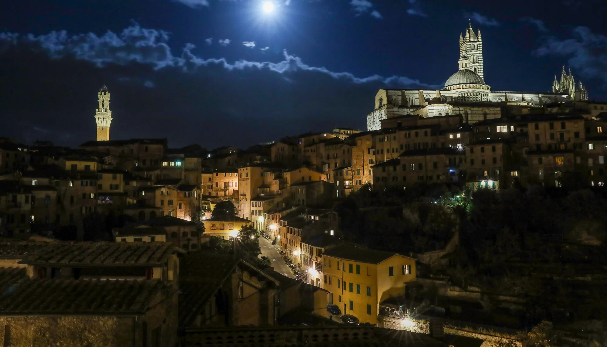 Siena Cathedral, Duomo di Siena, right, and the Mangia tower at night in Siena, Italy.