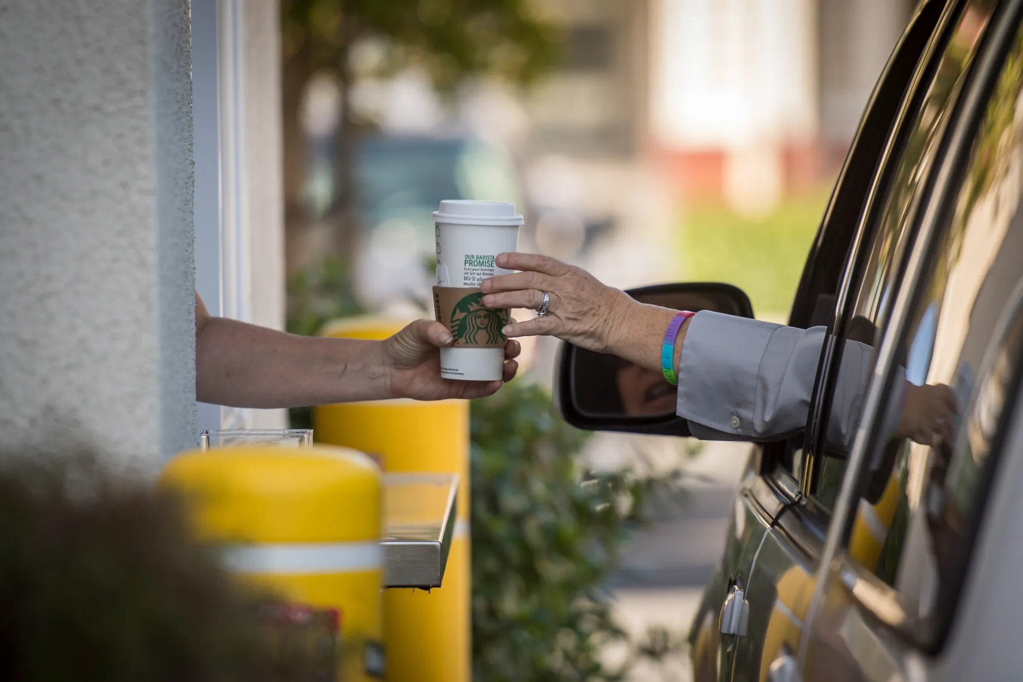 An employee passes a drink order to a customer at the drive-thru of a Starbucks Corp. coffee shop in Rodeo, California, U.S., on Monday, April 23, 2018. The world's largest coffee-shop chain is embracing the drive-thru lane. Eighty percent of all its new U.S. cafes will have them.