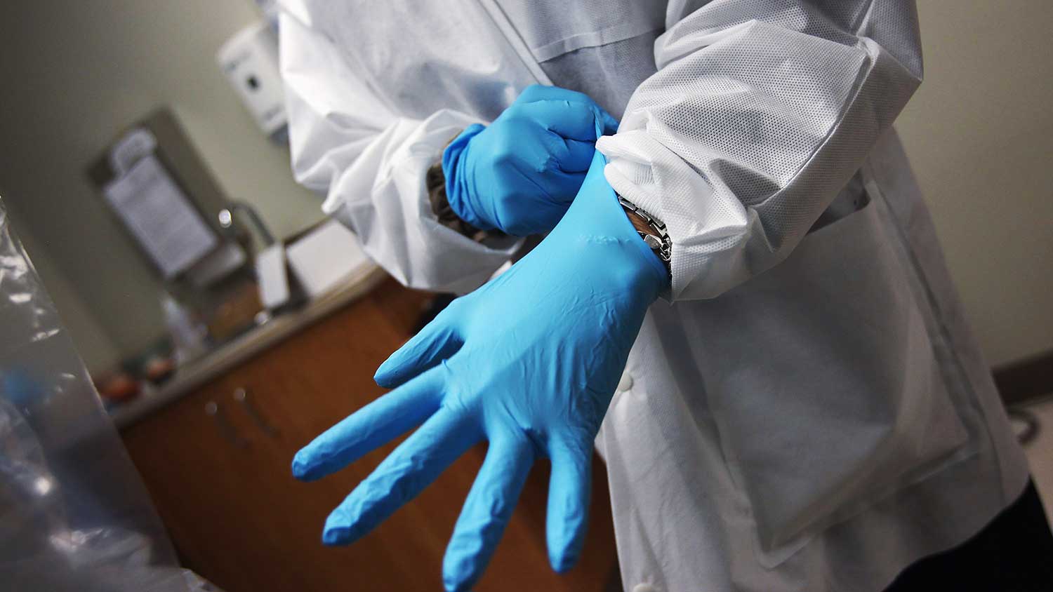 A dentist dons sterile gloves at a community health center on March 27, 2012 in Aurora, Colorado.
