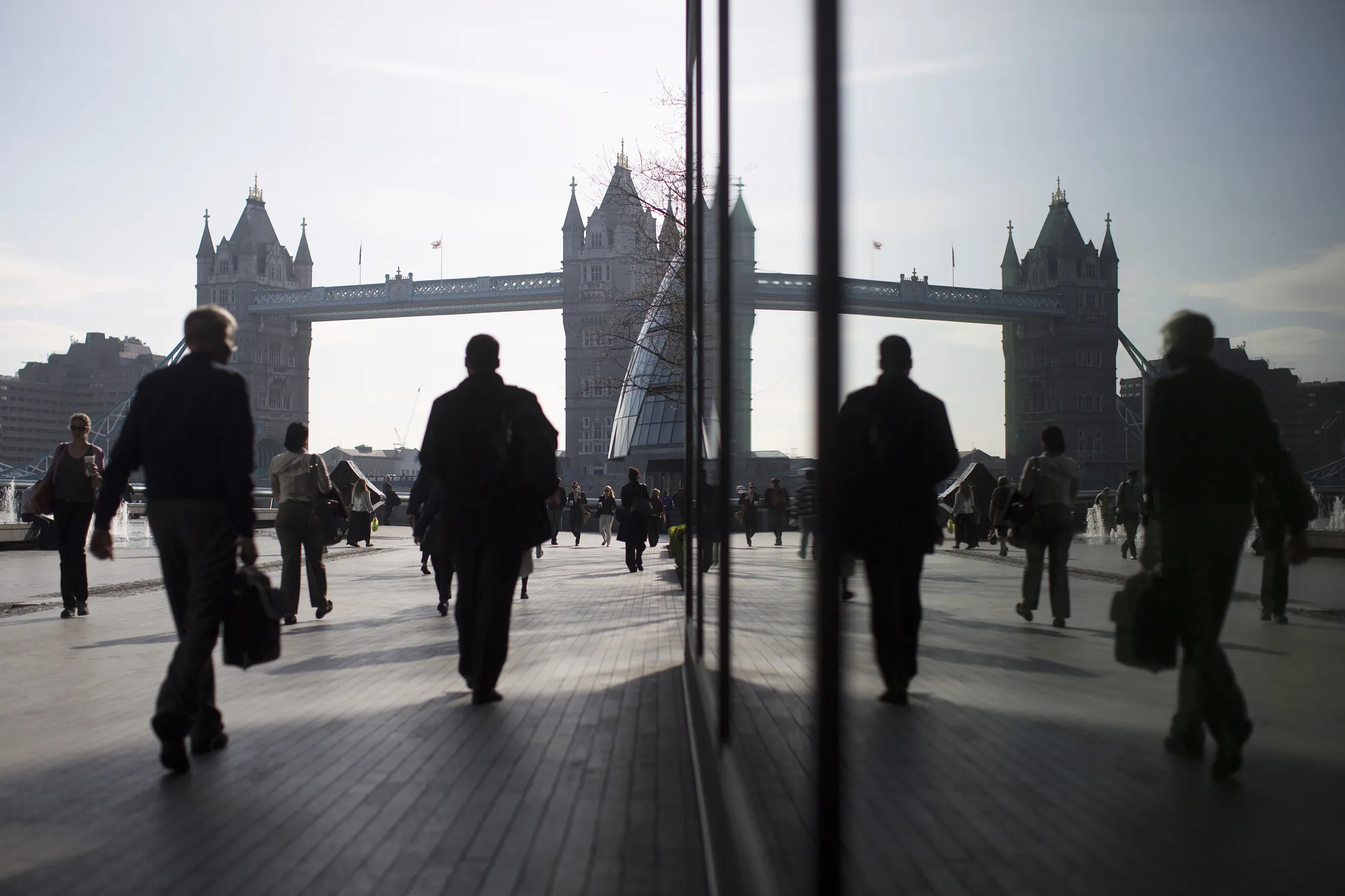 Pedestrians are seen walking through the More London office space against the backdrop of Tower Bridge in London, U.K.