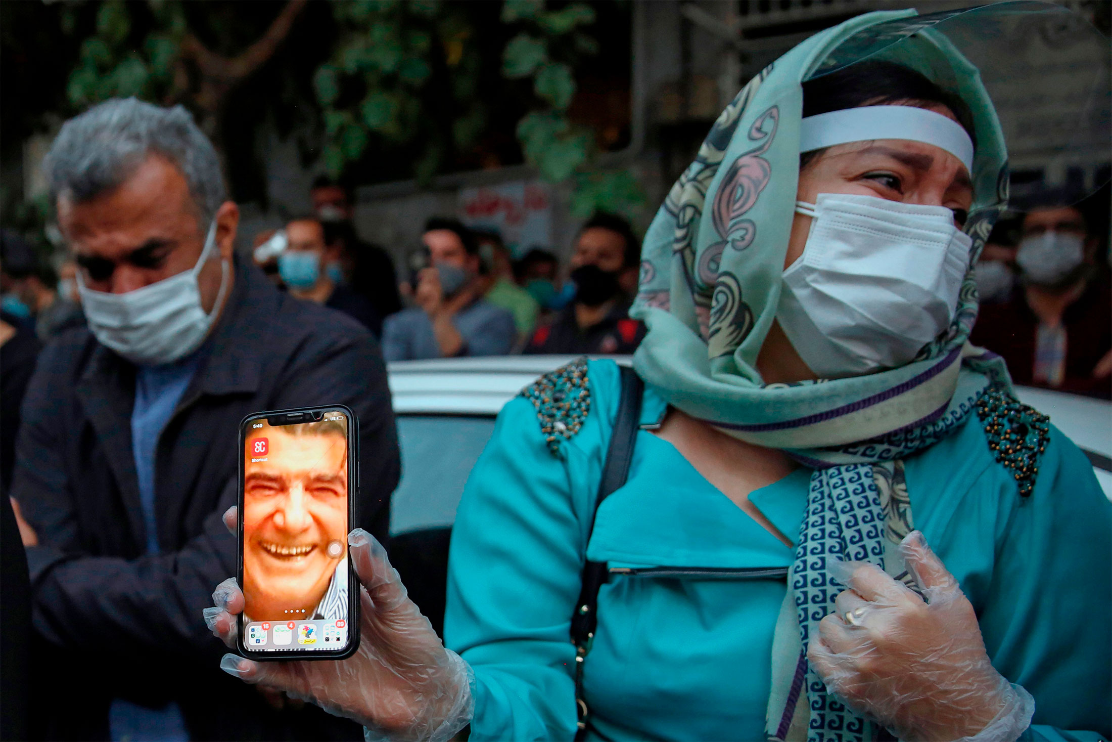 A fan of Iranian musician Mohammad Reza Shajarian displays his picture on her phone as people gather&nbsp;outside the hospital where he died, in Tehran,&nbsp;on Oct. 8.&nbsp;