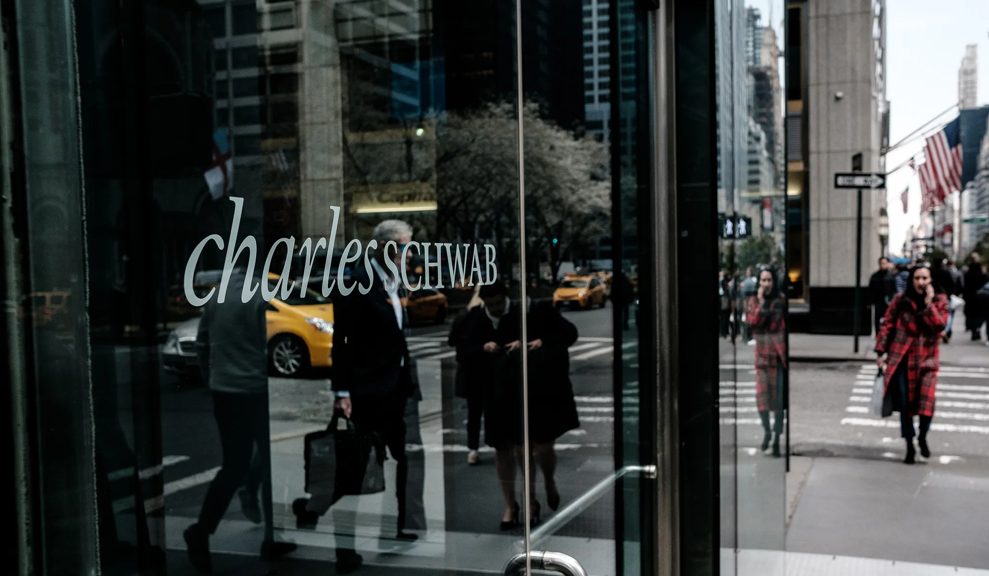Pedestrians pass in front of a Charles Schwab Corp. office building in New York.