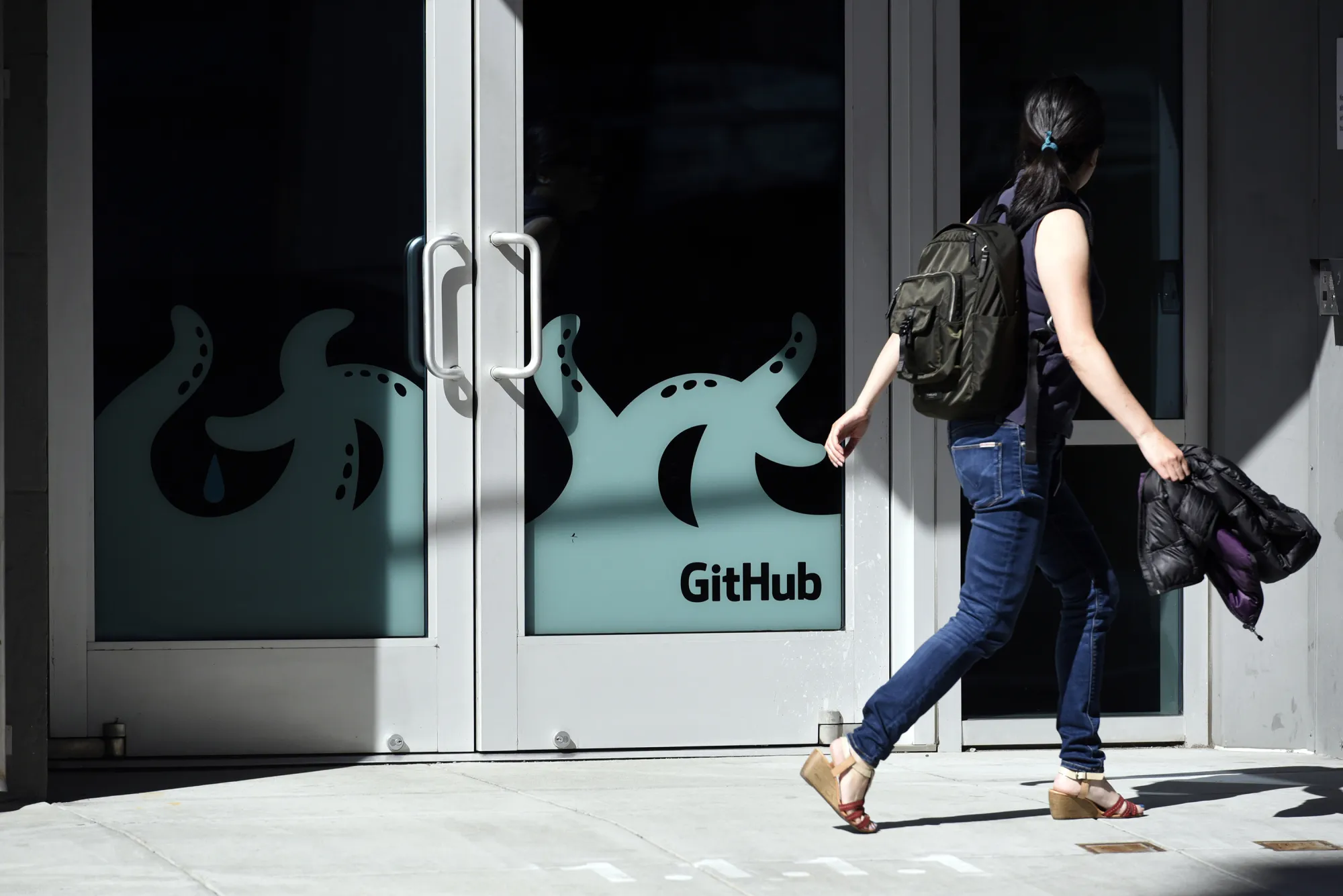 A pedestrian walks past the GitHub offices in San Francisco.