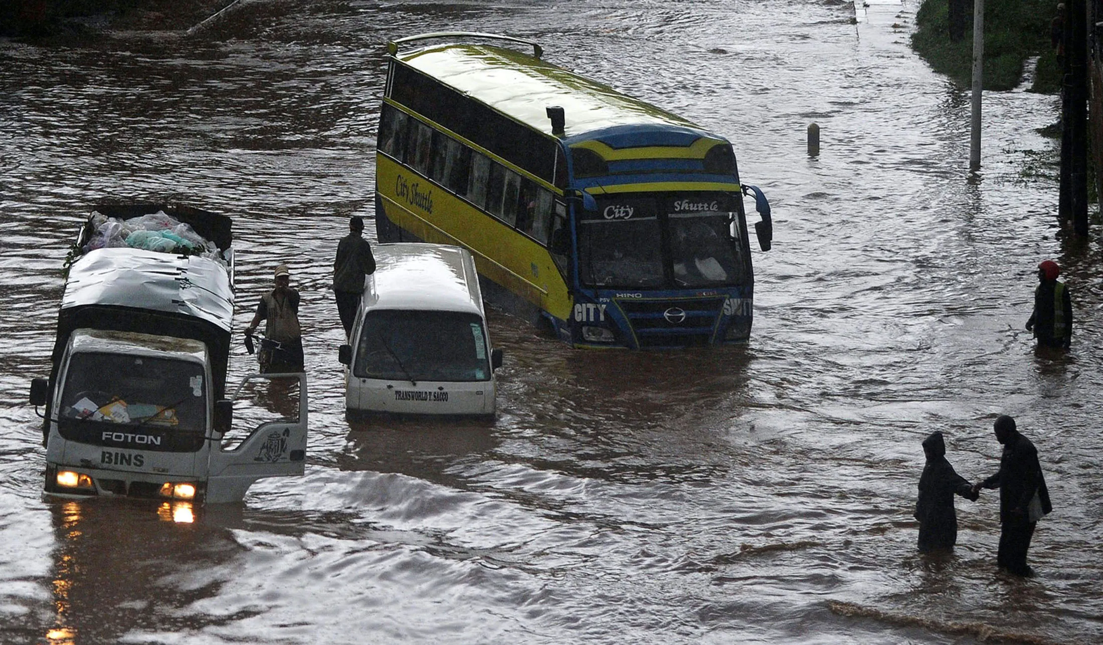 People attempt to cross through a flooded section of road, as others climb out of vehicles on April 29, 2016 in the Kenyan capital Nairobi that has been hit by heavy downpours as the long rains season starts. / AFP / TONY KARUMBA (Photo credit should read TONY KARUMBA/AFP/Getty Images)
