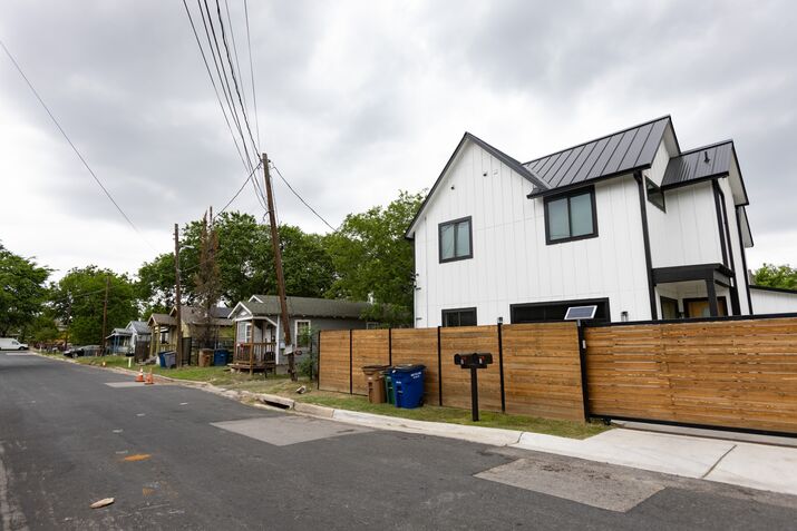 A new home, right, towers over residences on the same street in the Montopolis neighborhood of Austin in 2022. The booming Texas capital's efforts to revise its land development code and build more affordable housing have been thwarted by protests from homeowners.