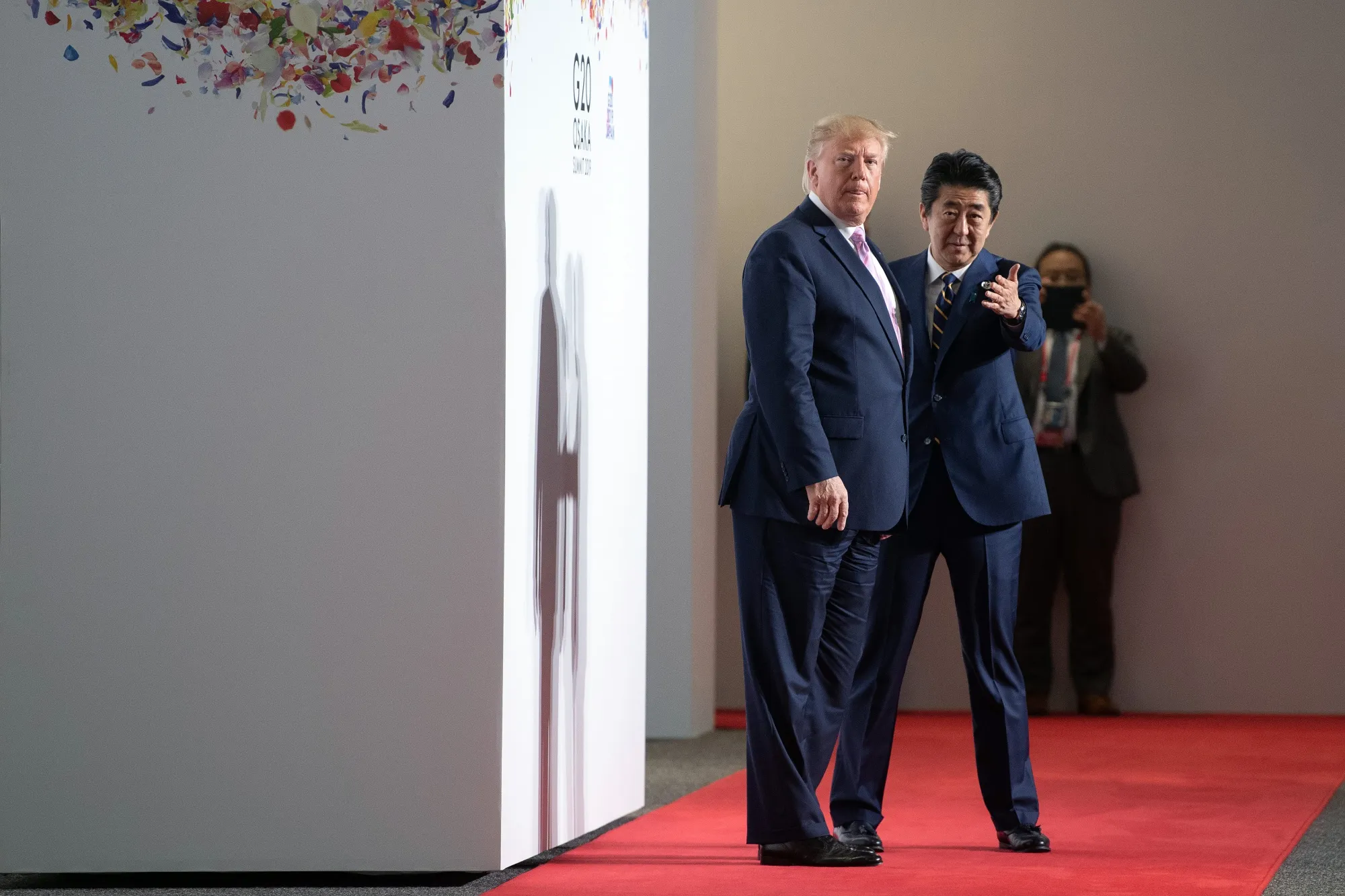 Shinzo Abe, Japan's prime minister, right, gestures as U.S. President Donald Trump looks on during a photo session&nbsp;at the Group of 20 (G-20) summit in Osaka on June 28, 2019.