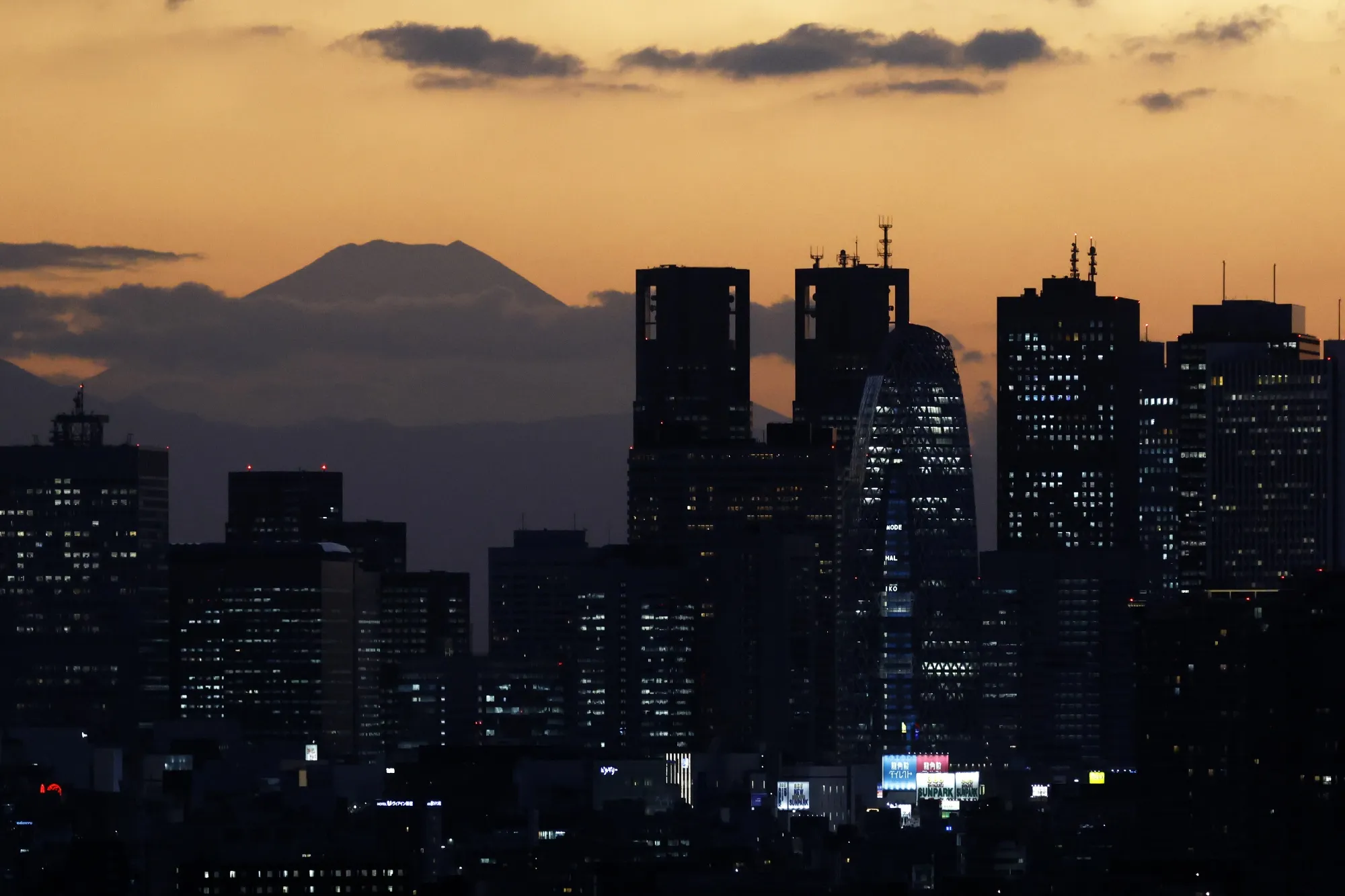 Mount Fuji and the Shinjuku skyline at dusk in Tokyo.