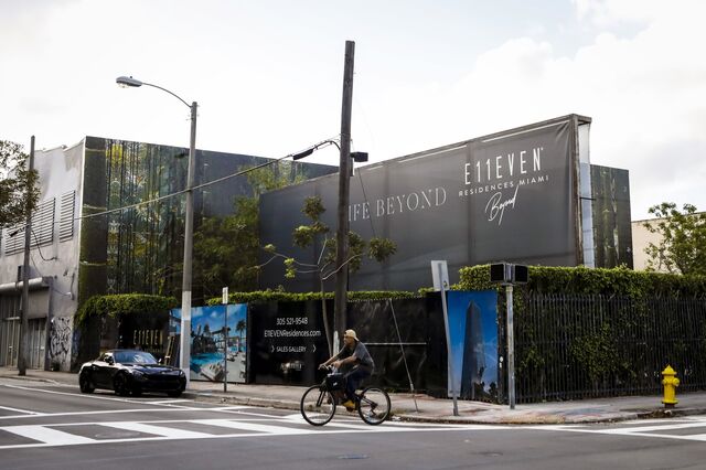 A person rides a bicycle past a billboard advertising for E11even Hotel and Residences tower.