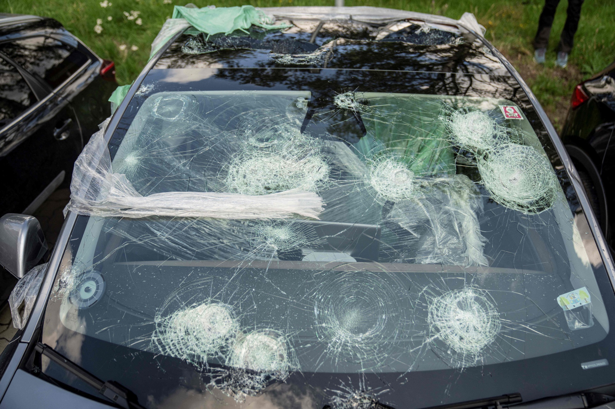A close-up shot of a car with large, circular cracks in its windshield.