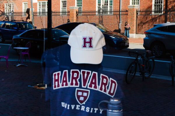 Harvard University is reflected in the window of a merchandise store.