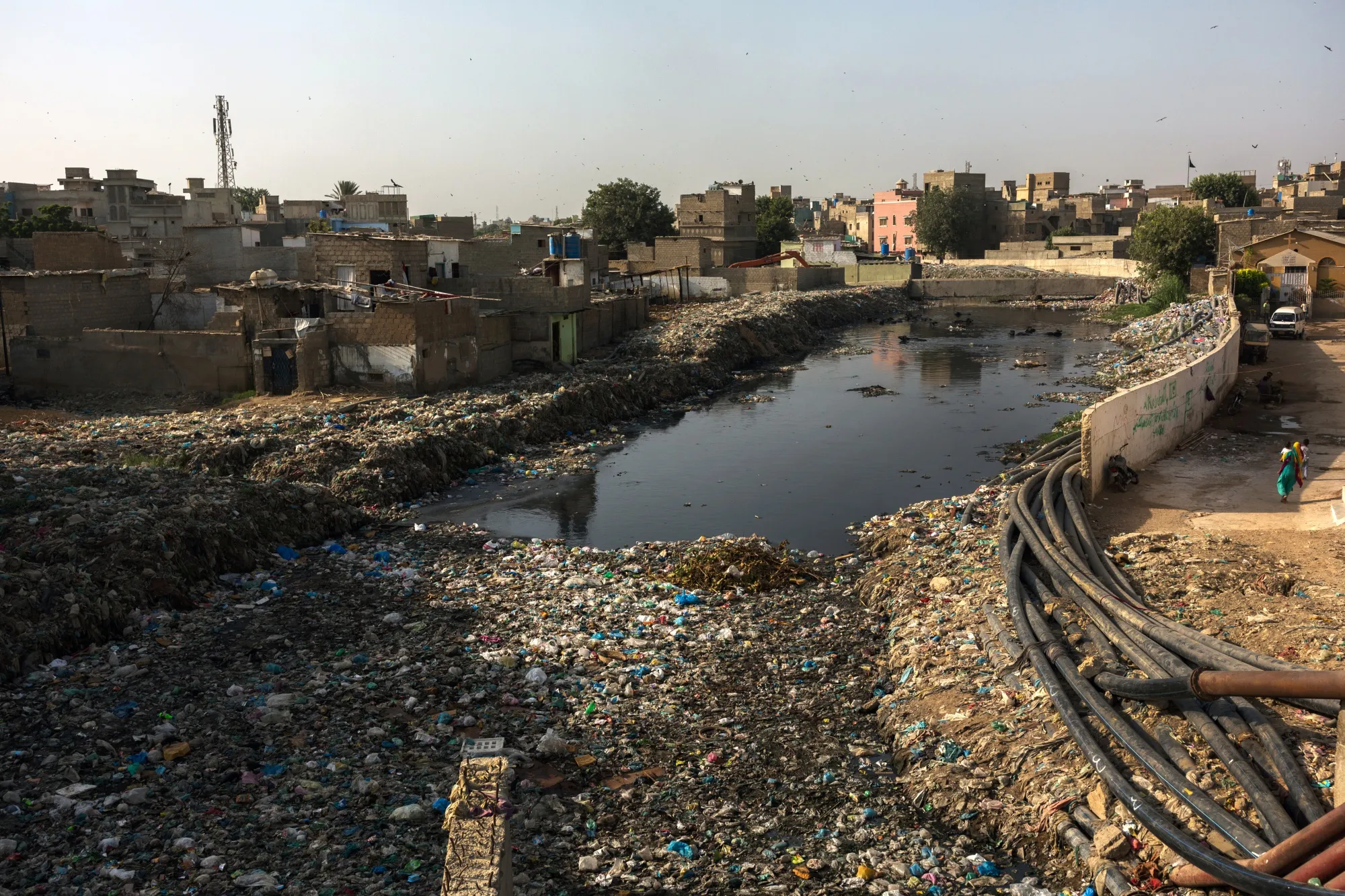 Water pipes run next to a waterway covered in garbage&nbsp;in Karachi.