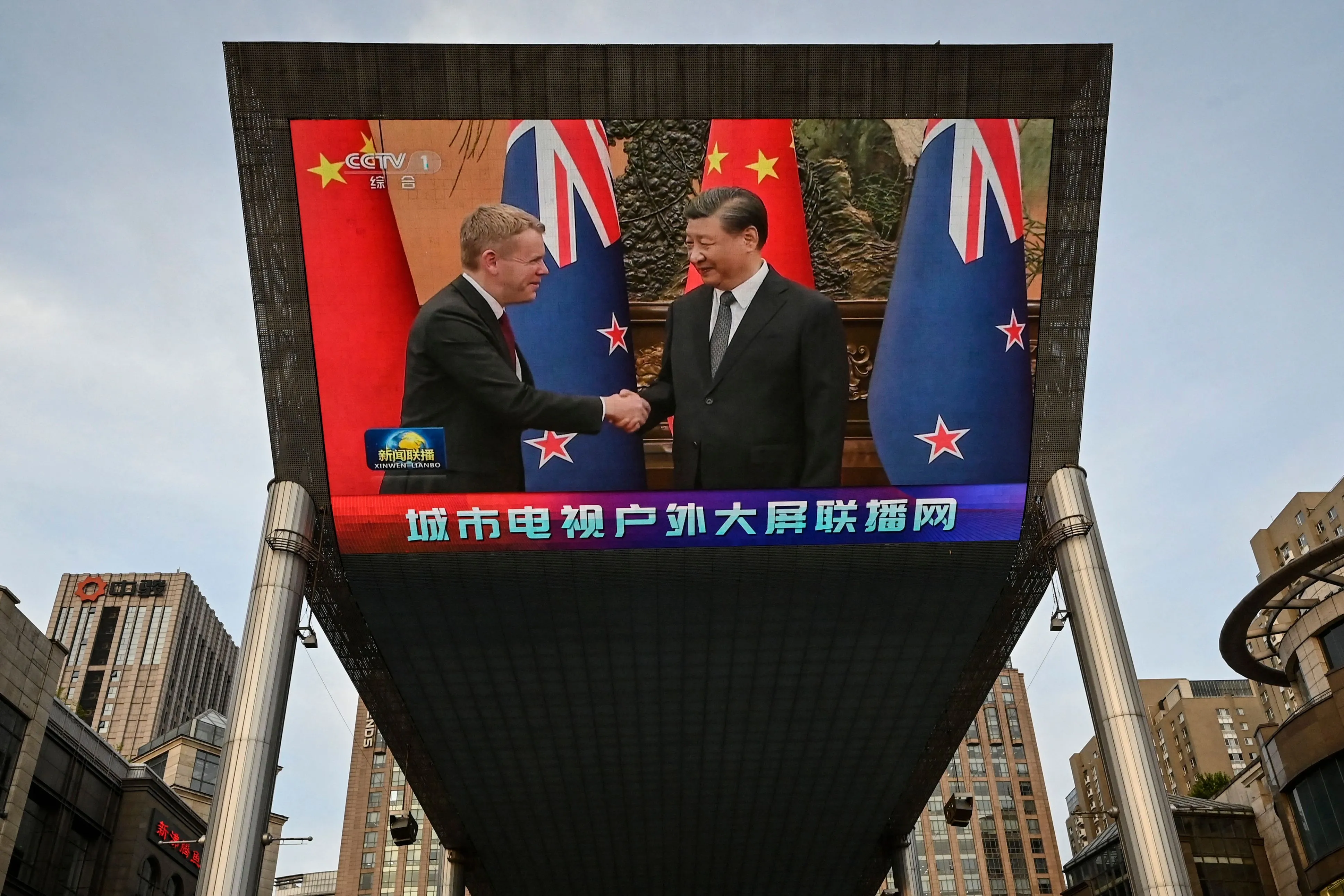 An outdoor screen shows news coverage of Xi Jinping, right, meeting Chris Hipkins at the Great Hall of the People, in Beijing on June 2.