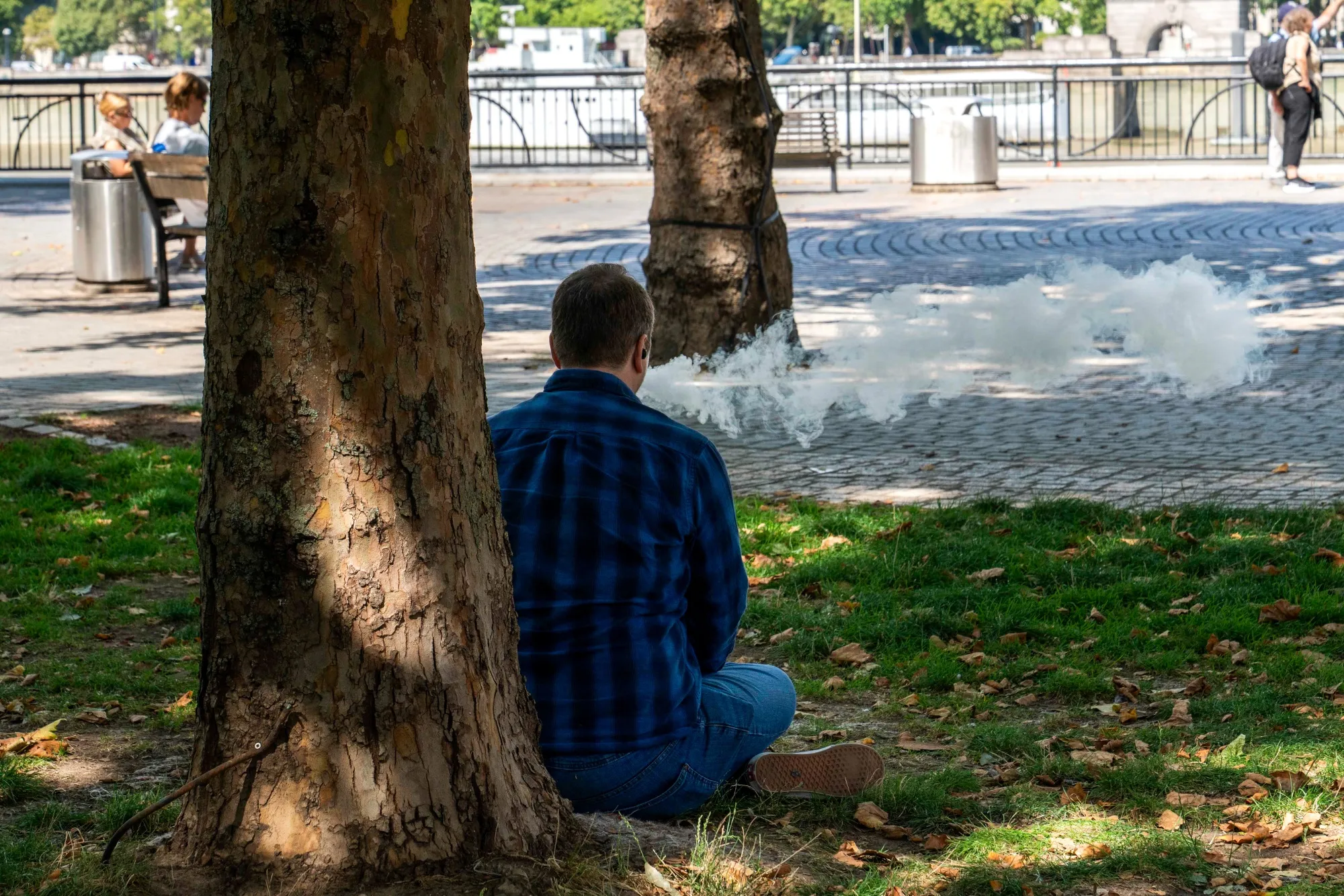 A man vapes under a tree in London