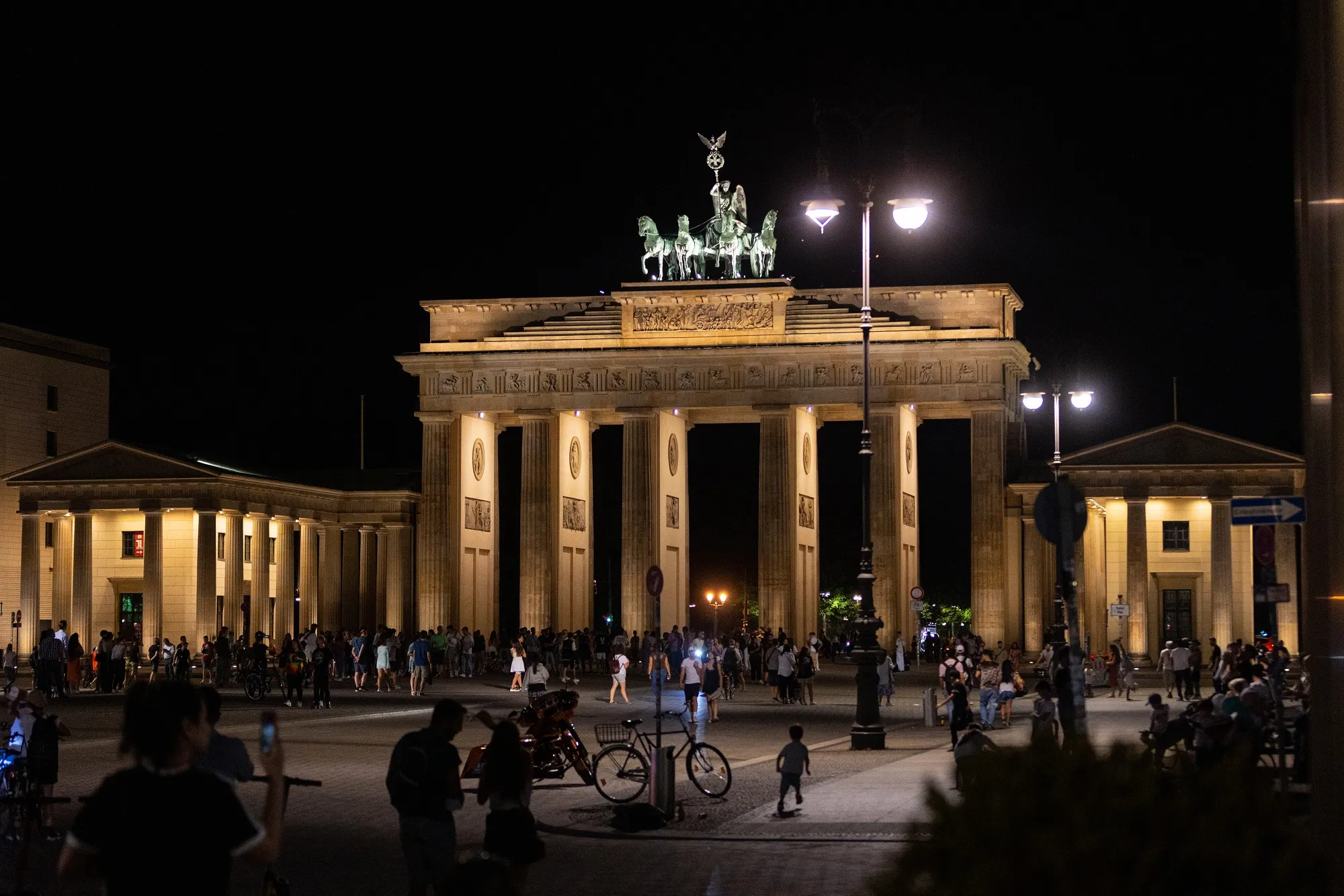 Visitors at the lit Brandenburg Gate at night in Berlin.