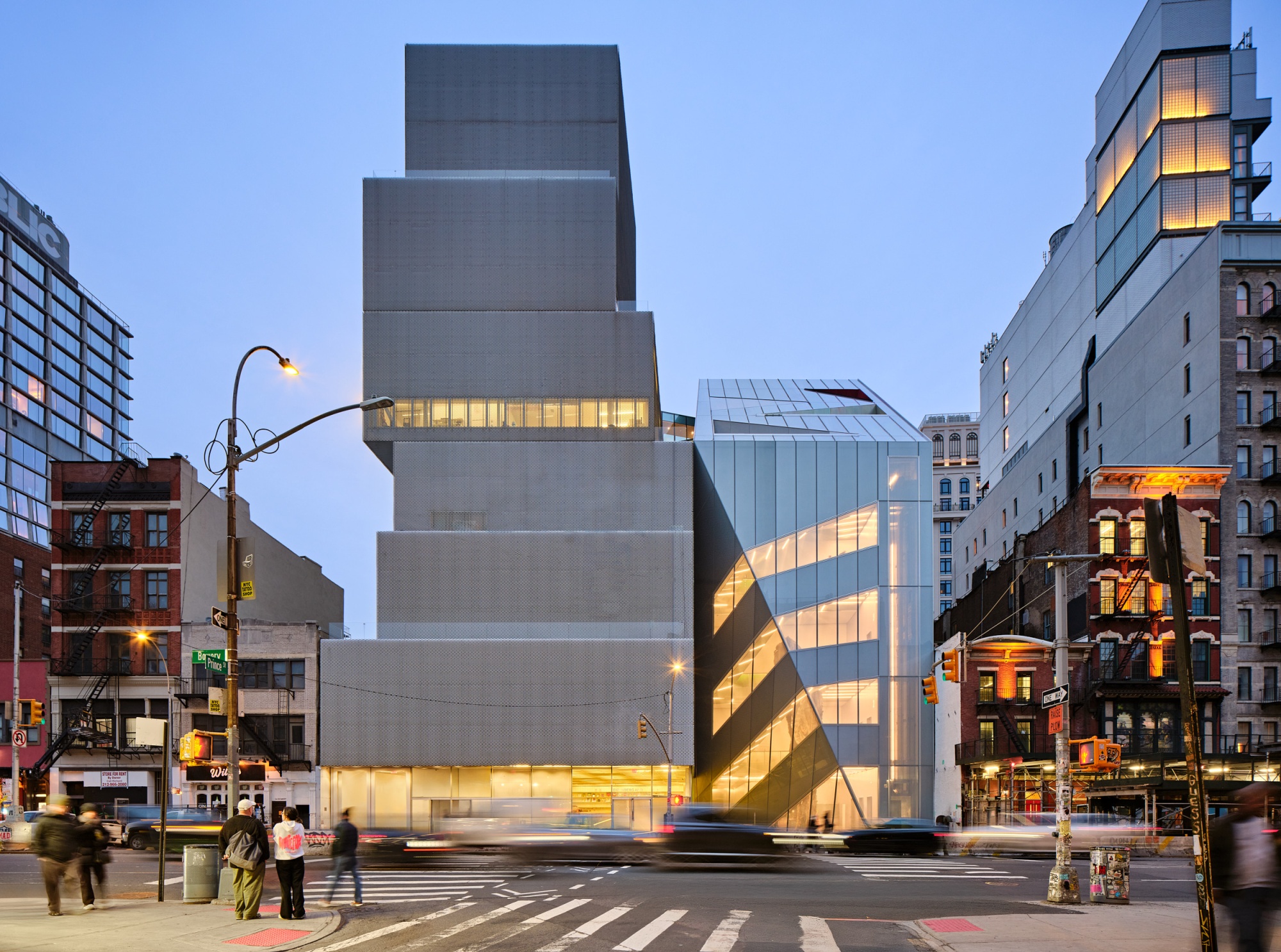 An expansion of the New Museum (right) designed by OMA contrasts the original building in more ways than one.