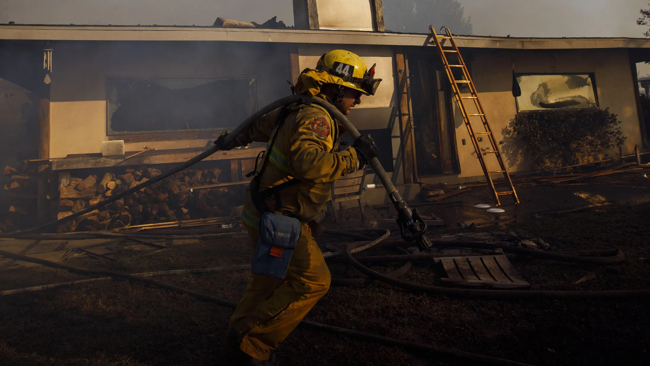 A firefighter pulls a hose line while working to save homes during the Skirball Fire in the Bel Air neighborhood of Los Angeles, California, on&nbsp;Dec.&nbsp;6, 2017.
