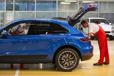 Employees check a Porsche Macan sport-utility vehicle (SUV) inside the Porsche AG factory in Leipzig.