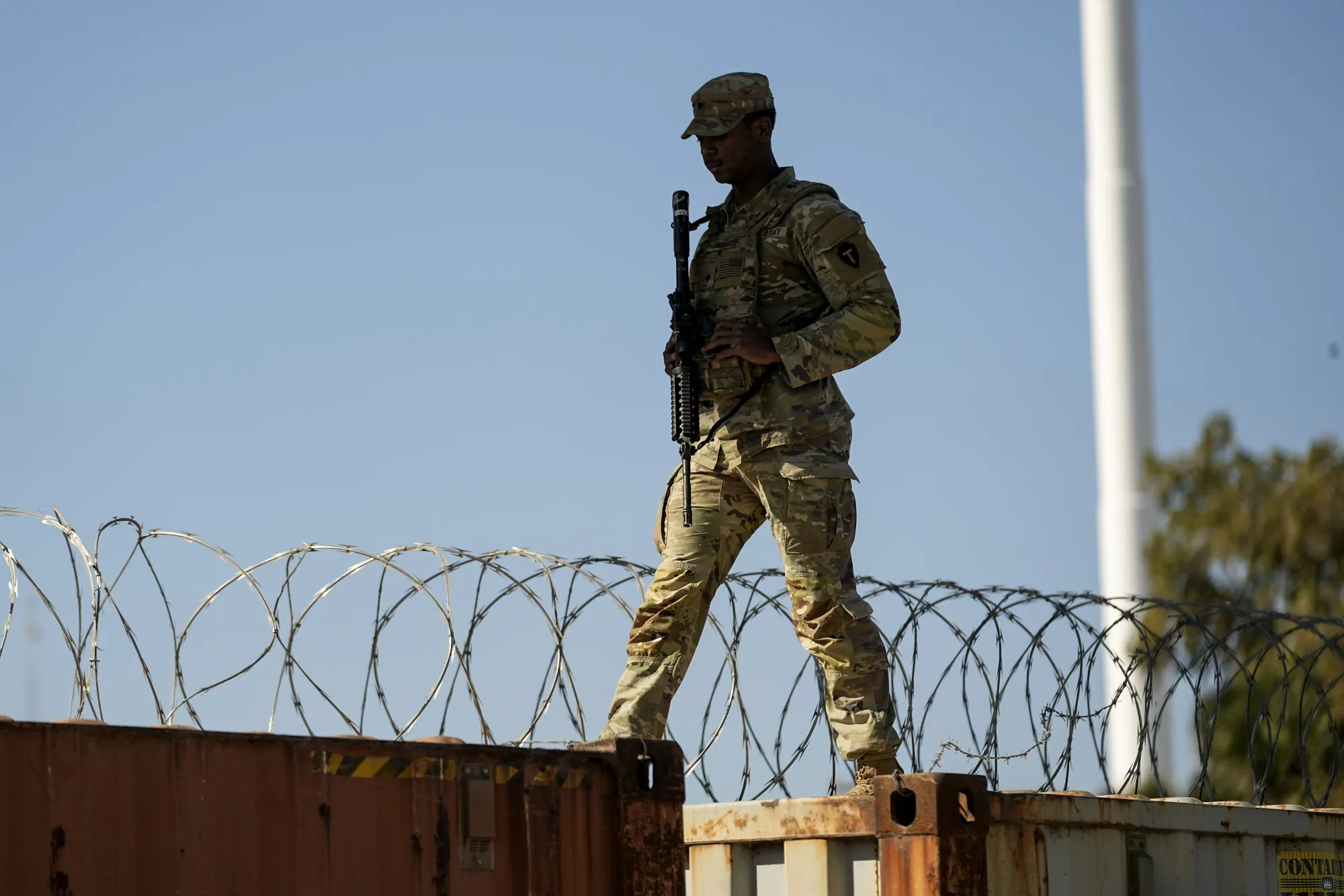 A guardsman walks on a barrier topped with concertina wire&nbsp;along the US-Mexico border in Eagle Pass, Texas.