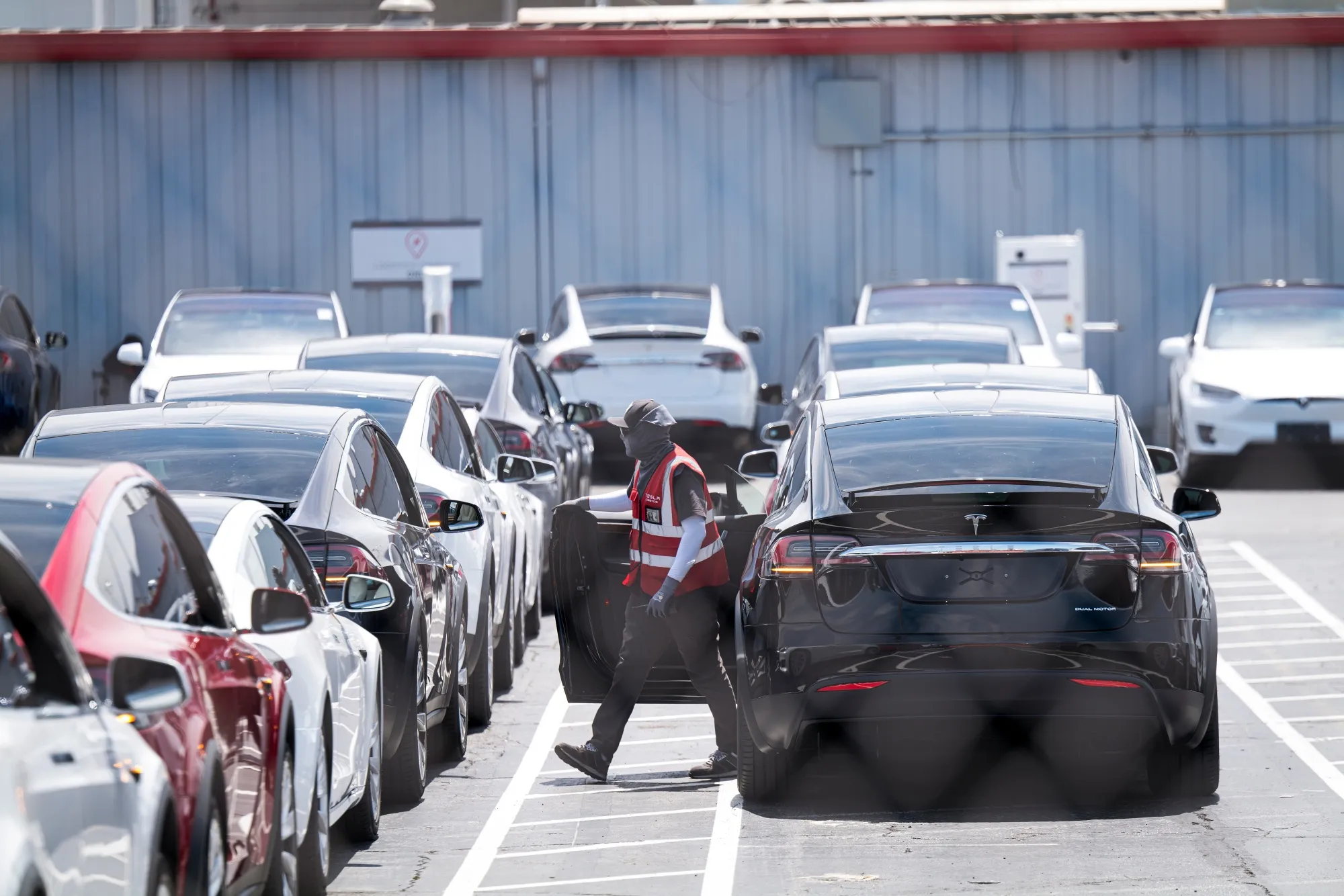 A worker wearing a face covering exits a Tesla vehicle at the company's assembly plant in Fremont, California, in August&nbsp;2020.