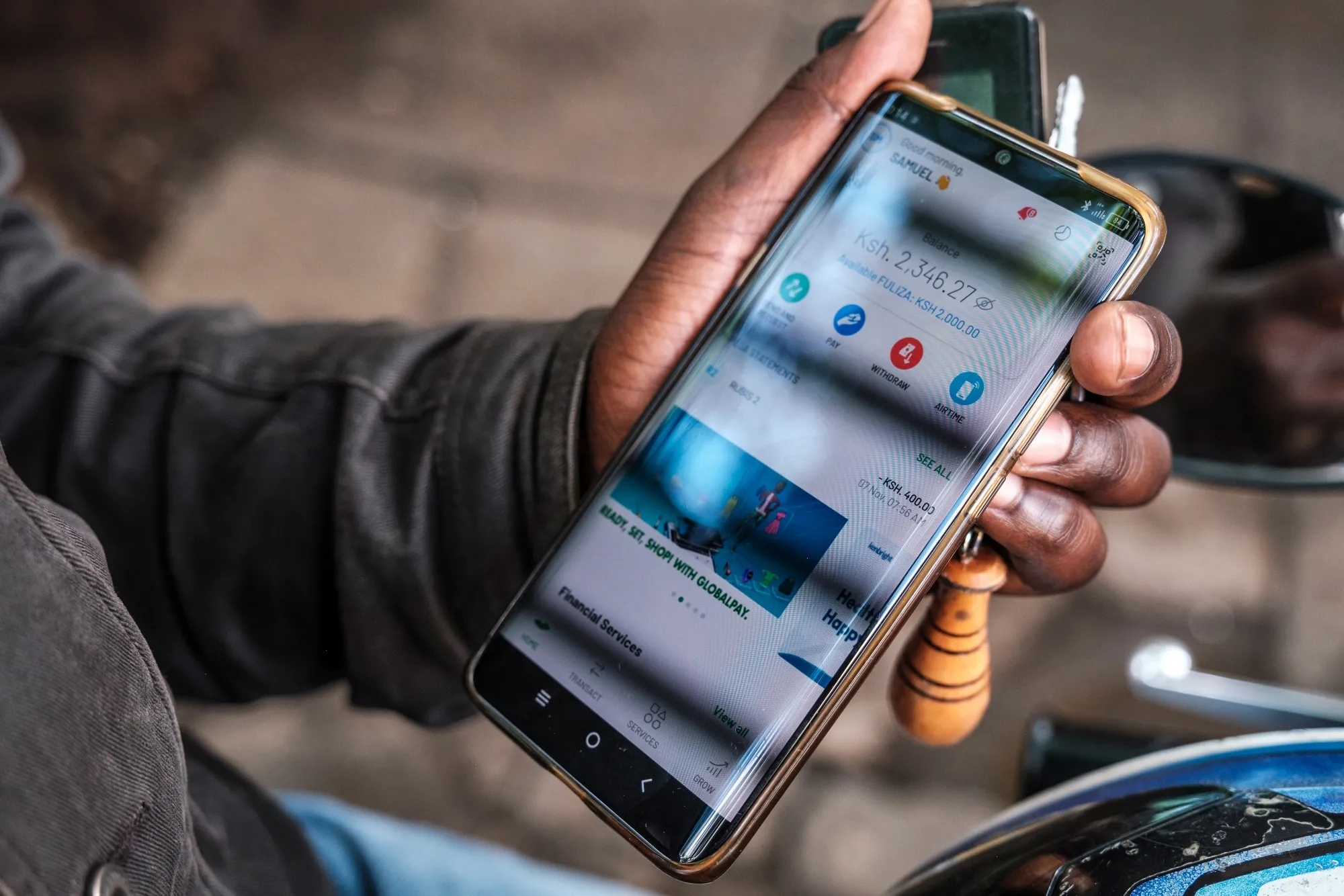 A man holds a mobile phone with the Safaricom Plc M-Pesa mobile banking services app in Nairobi, Kenya.