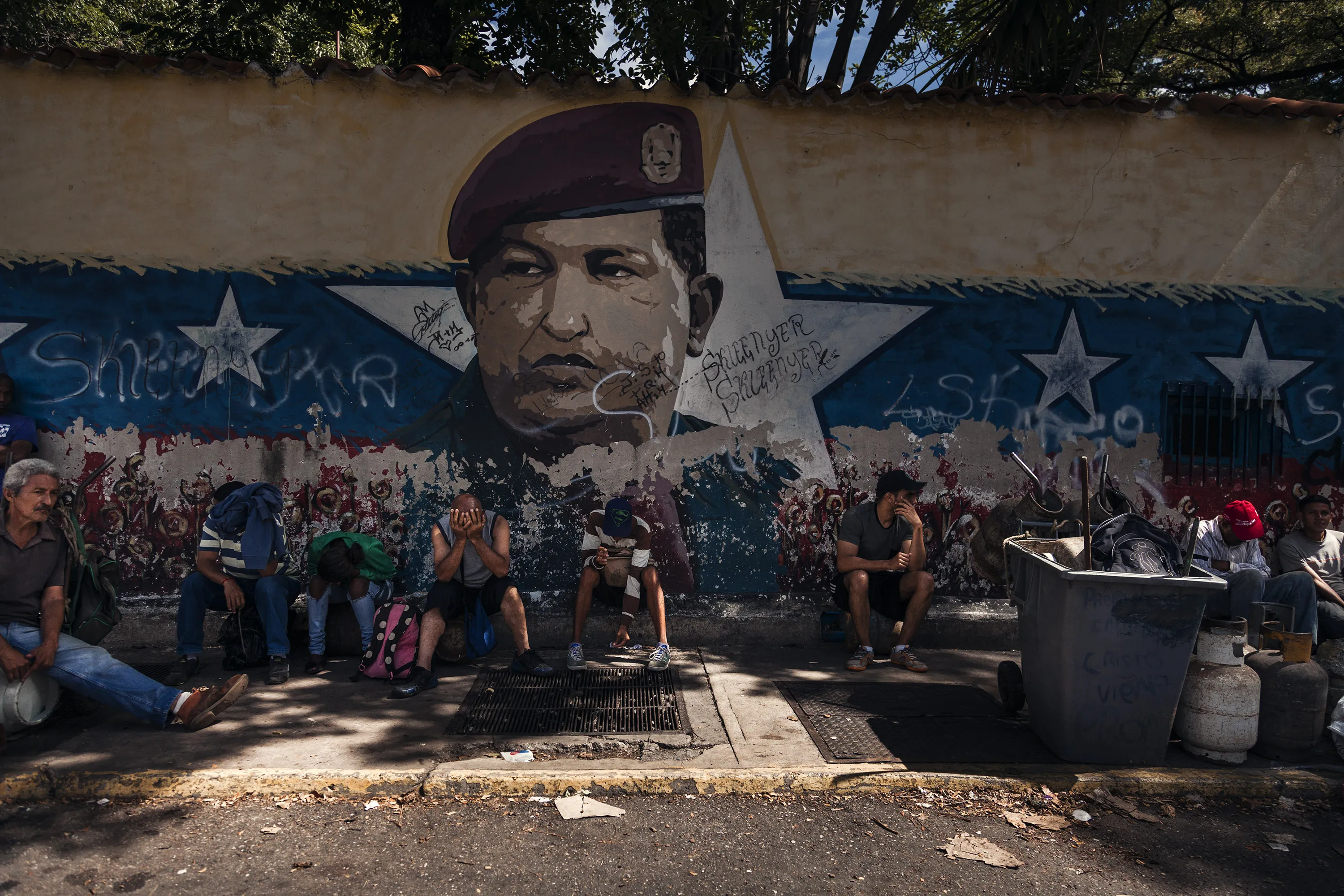 People wait in line for propane gas in front of a mural of the late Hugo Chavez in the Petare neighborhood of Caracas on Sept. 13, 2018.&nbsp;