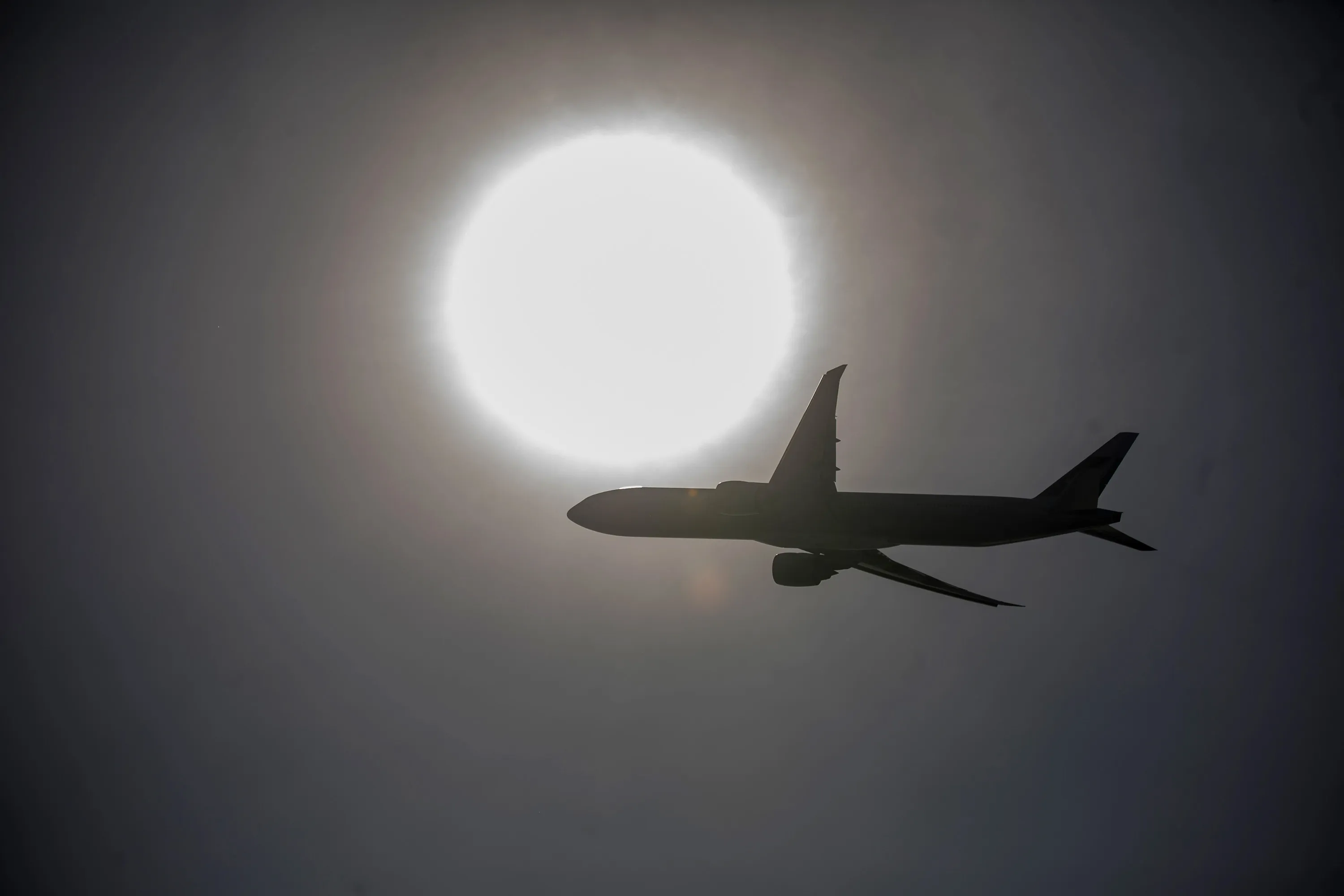 An aircraft is silhouetted as it flies over the Hong Kong International Airport.