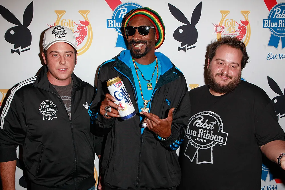 Snoop Dogg, Evan Metropoulos and Daren Metropoulos pose at the Snoop Dogg Presents: Colt 45 Works Every Time at The Playboy Mansion Party with Evan and Daren Metropulos in Beverly Hills, California.
