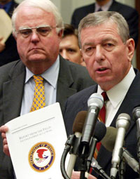 Former U.S. Attorney General John Ashcroft (right) holds up a copy of a Justice Department Patriot Act report during a news briefing with Representative James Sensenbrenner in 2004