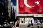 Pedestrians pass a giant Turkish national flag hanging above a DenizBank AS bank branch in Istanbul.
