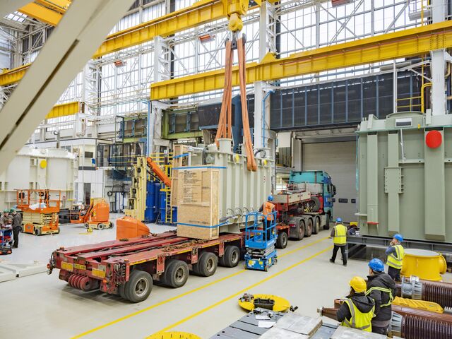 Workers transporting a transformer prepare to leave the GE Vernova factory. Using public roads requires special vehicles and a security escort.