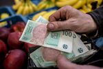 A vendor holds 100 Czech koruna banknotes at a vegetable stall in Holesovicka market hall in central Prague, Czech Republic, on Thursday, Jan. 4, 2017. The Czech Republic posted its biggest ever budget surplus last year after the government spent less than planned and economic growth boosted tax receipts, a rare success that ruling party leaders seized on to stake out their positions before fall elections.
