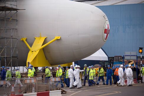 Workers pass the bulbous bow section of the Royal Navy's second Queen Elizabeth class aircraft carrier, the Prince of Wales, manufactured by the Aircraft Carrier Alliance, a joint operation between BAE Systems, Thales SA and Babcock International Group Plc, at Babcock shipyard in Rosyth, U.K., on March 25, 2014.