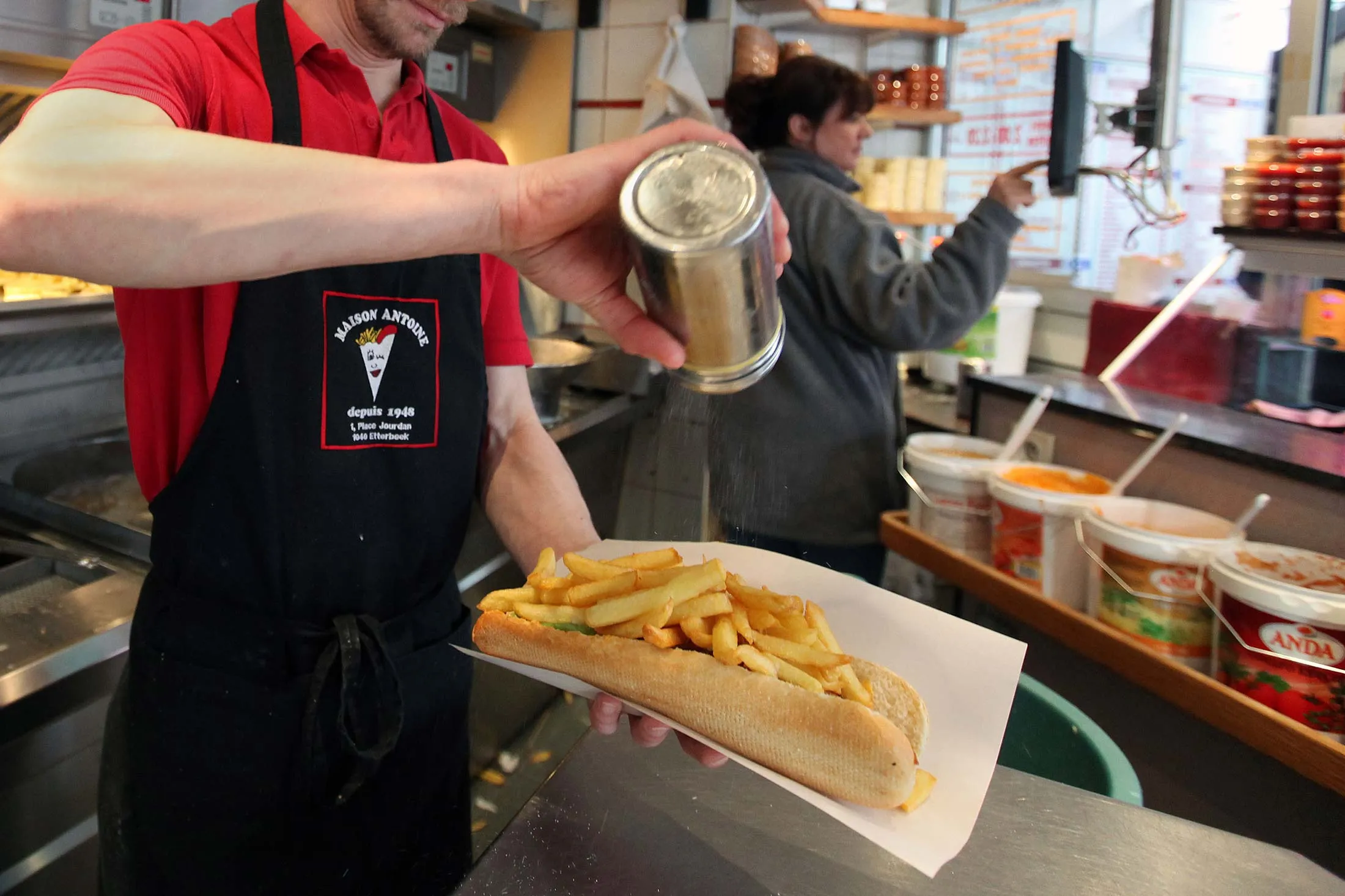 A worker prepares a mitraillette (fries submarine sandwich) at 'fritkot' Maison Antoine at Place Jourdan in Brussels, Thursday Feb. 4, 2010.
