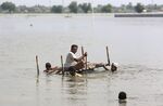 People use a cot to salvage belongings from their nearby flooded home in Baluchistan province, Sept. 3.