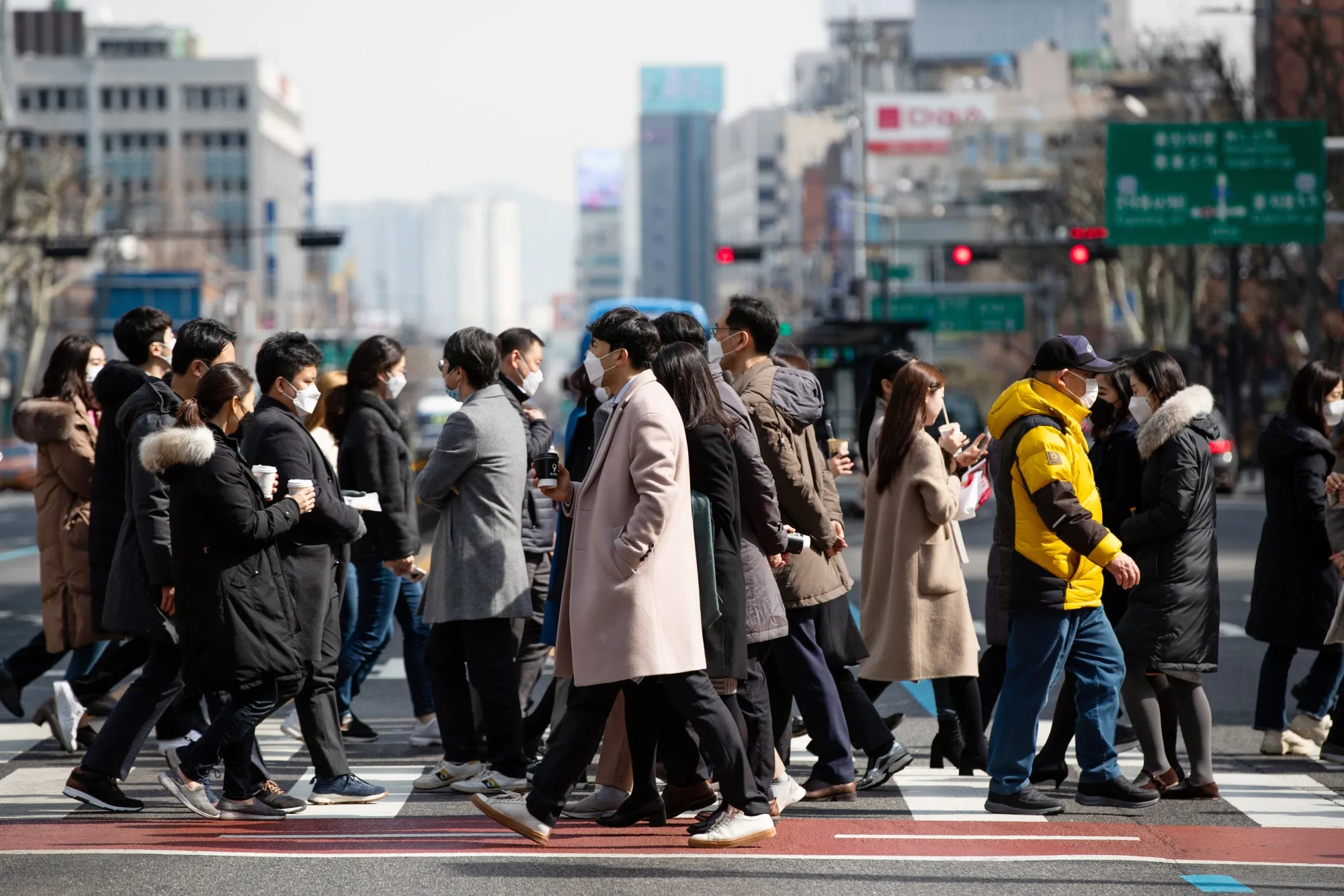 Pedestrians wearing protective masks cross a road in Seoul.