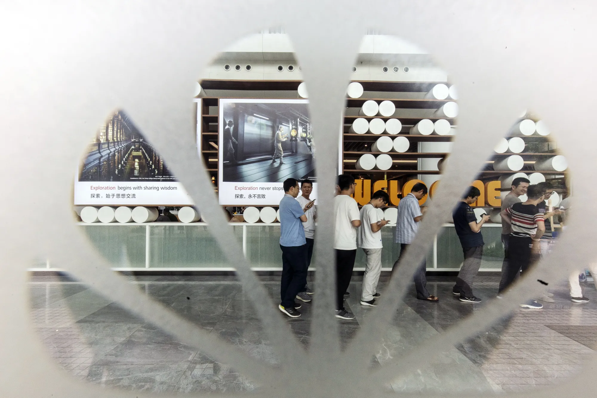 Employees are seen through a Huawei&nbsp;logo on a window at the company's headquarters in Shenzhen.