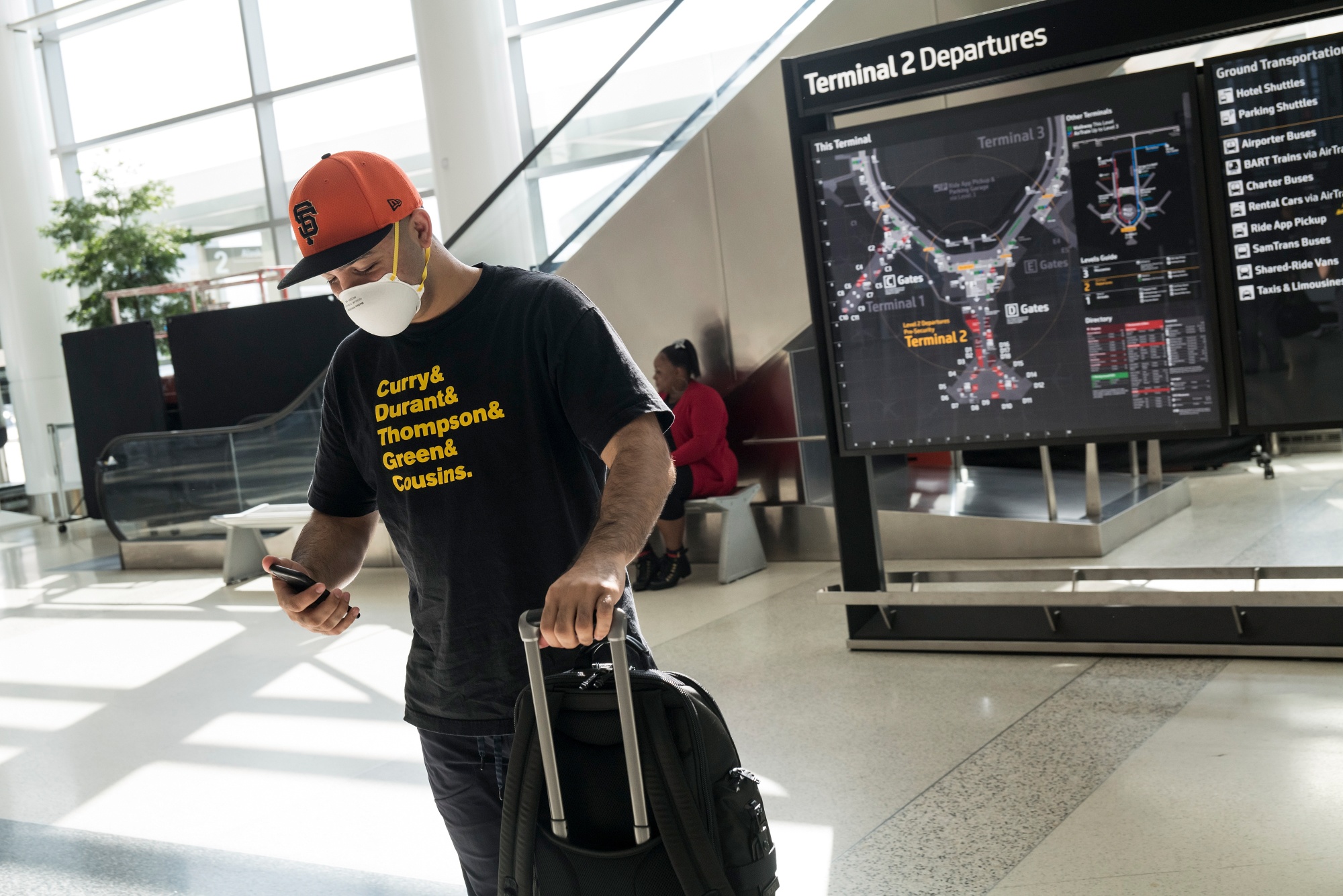 A traveler wearing a protective face mask looks at a mobile phone at San Francisco International Airport in San Francisco.