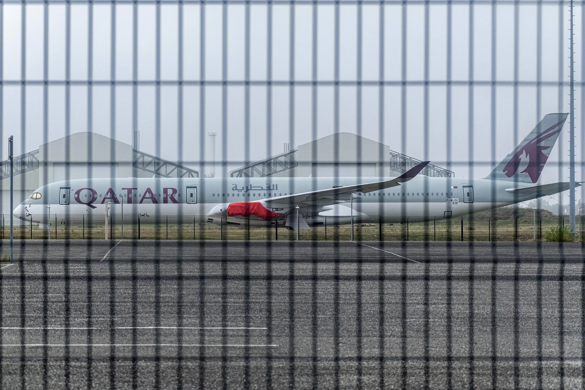 A fence surrounds a Qatar Airways Airbus plane.