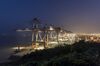 Trucks drive past gantry cranes at the Yangshan Deepwater Port, operated by Shanghai International Port Group Co. (SIPG), in the early morning in Shanghai, China, on Wednesday, Aug. 7, 2019. Trump's threat to raise tariffs on all Chinese goods last week shattered a truce reached with Xi just weeks earlier, unleashing tit-for-tat actions on trade and currency policy that risk accelerating a wider geopolitical fight between the world's biggest economies.