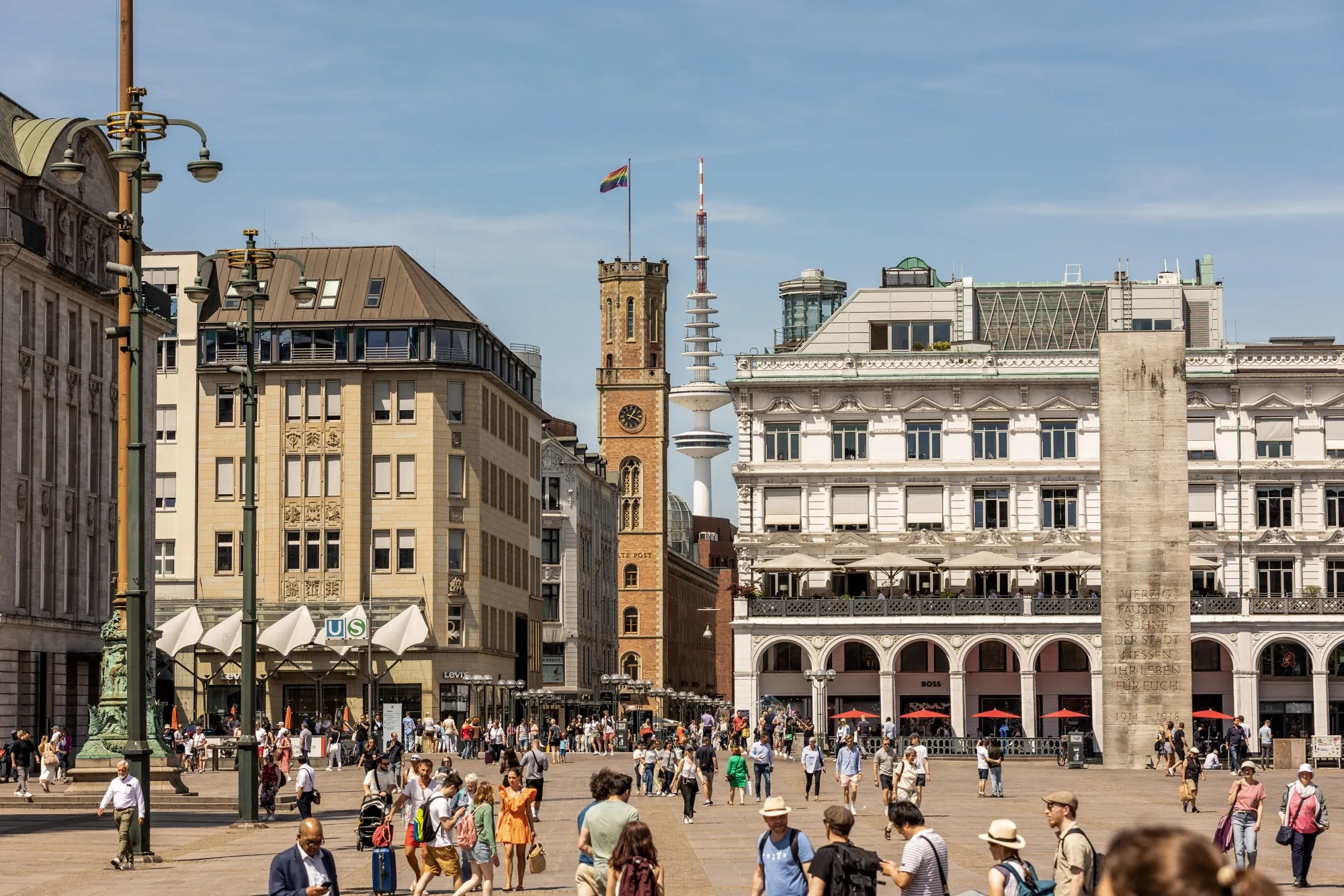 Pedestrians pass through a square near the town hall in Hamburg, Germany.
